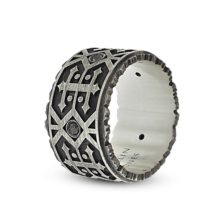 Front side angle of black diamond men’s wedding band. Oxidized silver detailing features alternating navajo-style designs; a grid of double-sided arrows with dots, and 2 rows of side-by-side zig-zag lines with centered round black diamond.