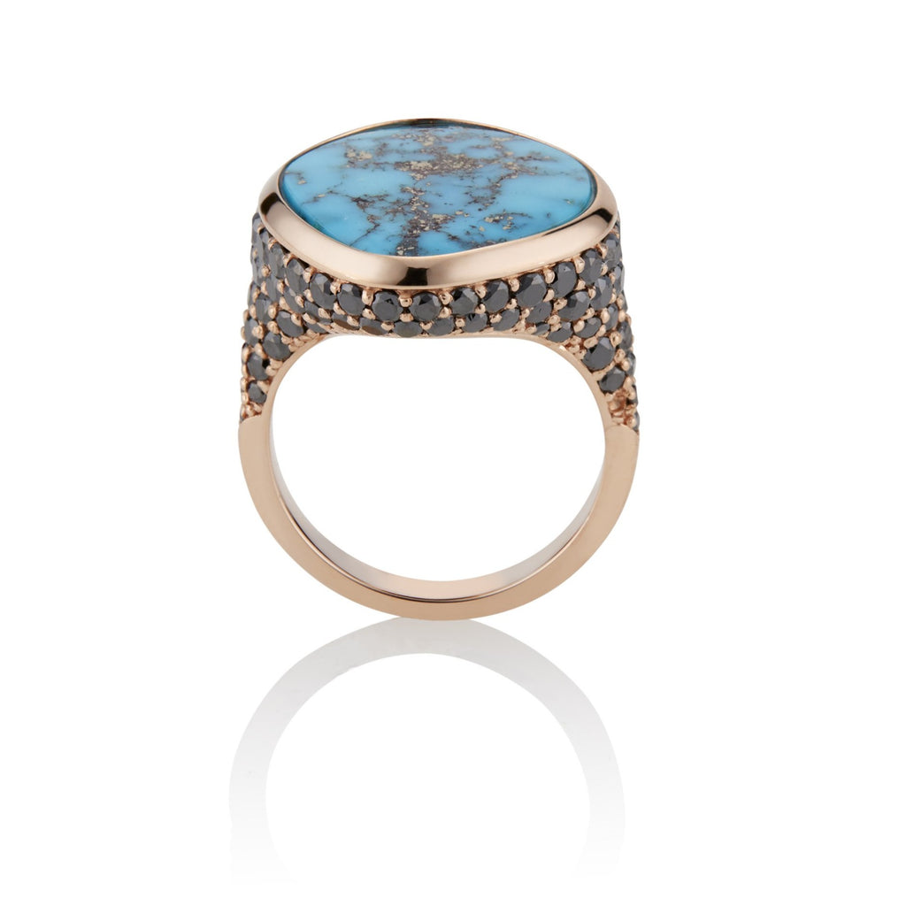 Side view. Custom turquoise rose gold ring with pave-set black diamonds beginning just below the setting, extending down to the mid shank. Several rows of black diamonds follow the shape of the ring, wrapping under the setting like snake scales.