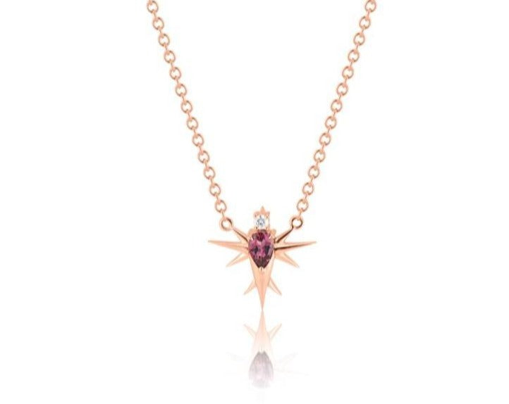 Front view of abstract bird pendant necklace connected to a rose gold round-link chain. A pear-shaped pink tourmaline stone forms the bird’s body, topped with a round diamond head. Rose gold spikes extend from the body to form wings and a tail. 