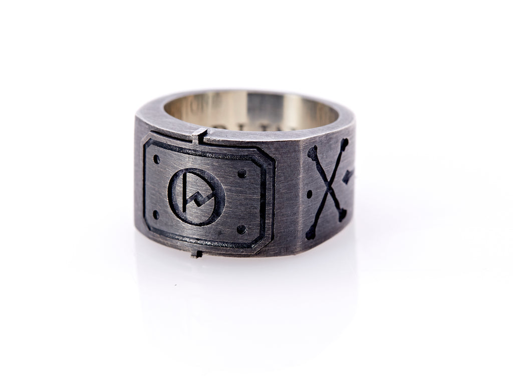 Oxidized sterling silver men’s signet ring with a thick flat band hand-crafted in New York. Semi-raised octagonal engraved top cap with a customizable insignia design of an engraved letter “O” in Old English Style lettering and 4 engraved dots at each corner. The initial on the ring is surrounded by a bold black engraved border that follows the inside edge of the rectangle. The rectangle’s top and bottom edge is accented by a small lip in the center that wraps around the corner edge of the ring.