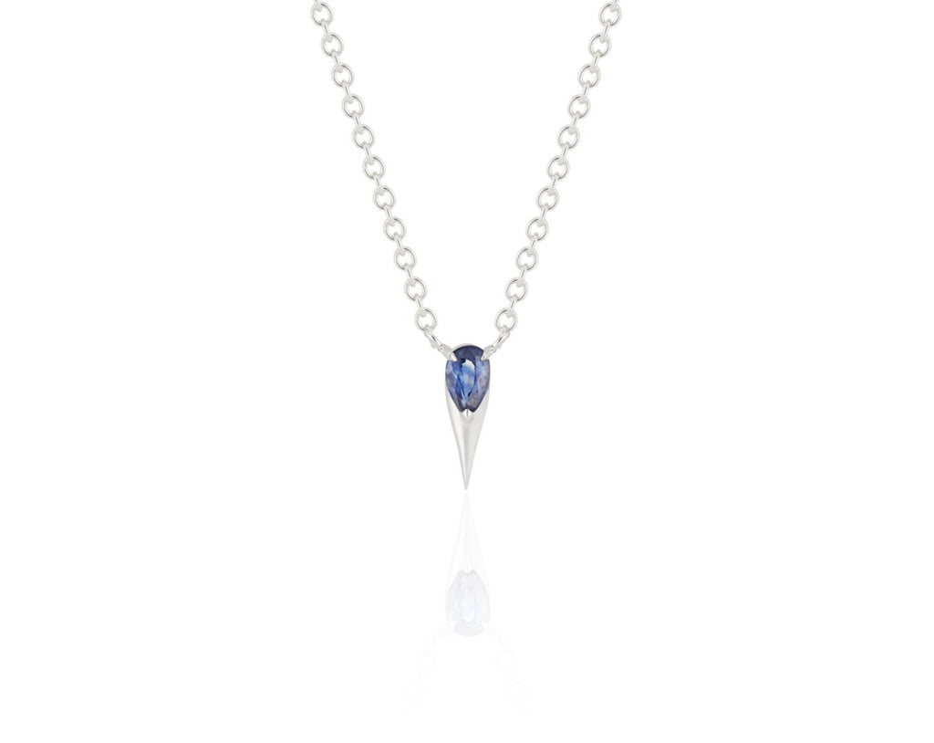 Front view of unique blue sapphire pendant necklace connected to a white gold round-link chain by 2 angled white gold prongs. The pear-shaped blue sapphire stone is set at the top of a white gold spike that drops below, forming a water droplet shape. 
