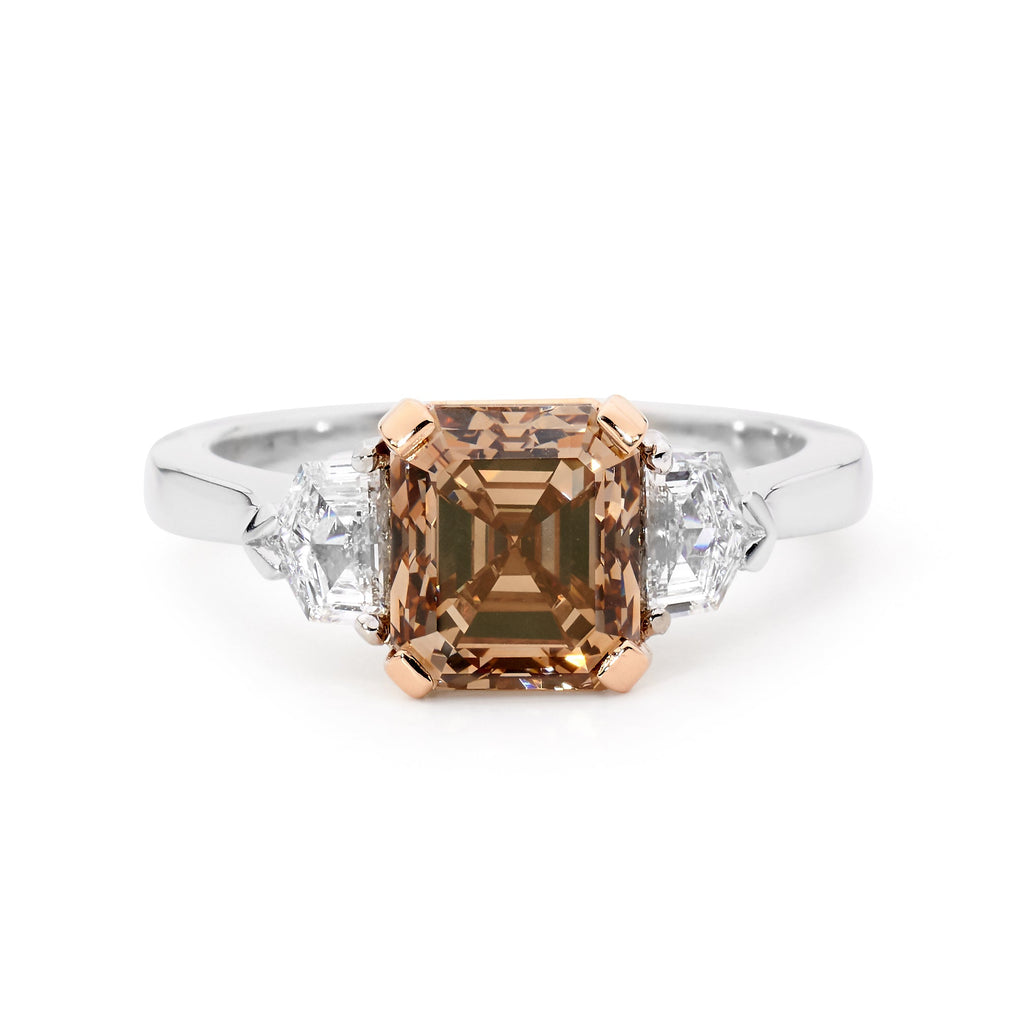 White gold ring with a central Asscher cut champagne diamond flanked by two smaller white diamonds.