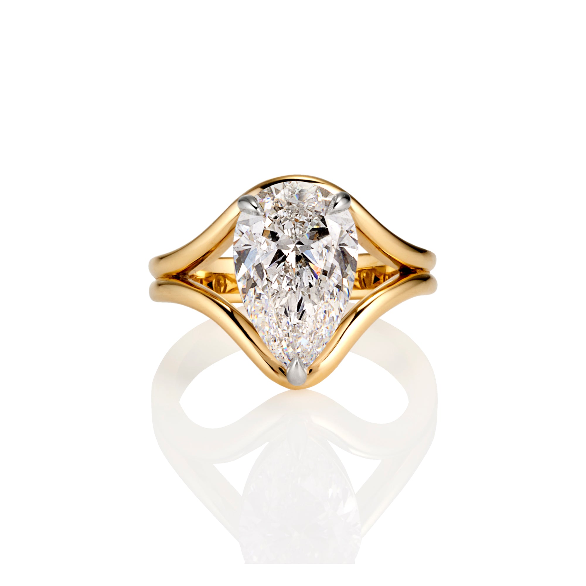 A yellow gold ring featuring a pear-cut diamond center stone in a split-shank setting, shown on a clean white background with a soft reflection below.
