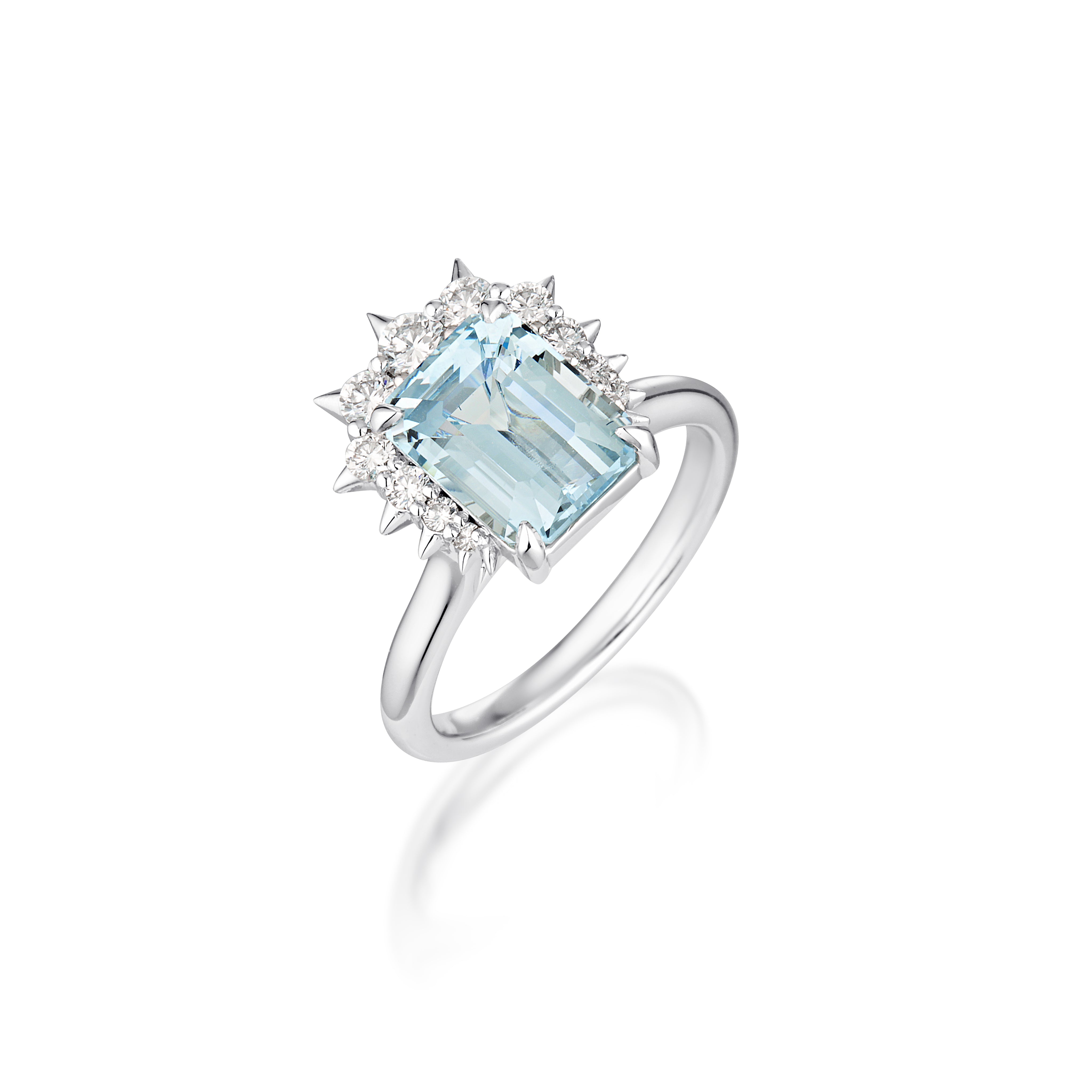 Standing upright a Alternative engagement ring with emerald-cut aquamarine gemstone surrounded by small diamonds, set on white gold band.