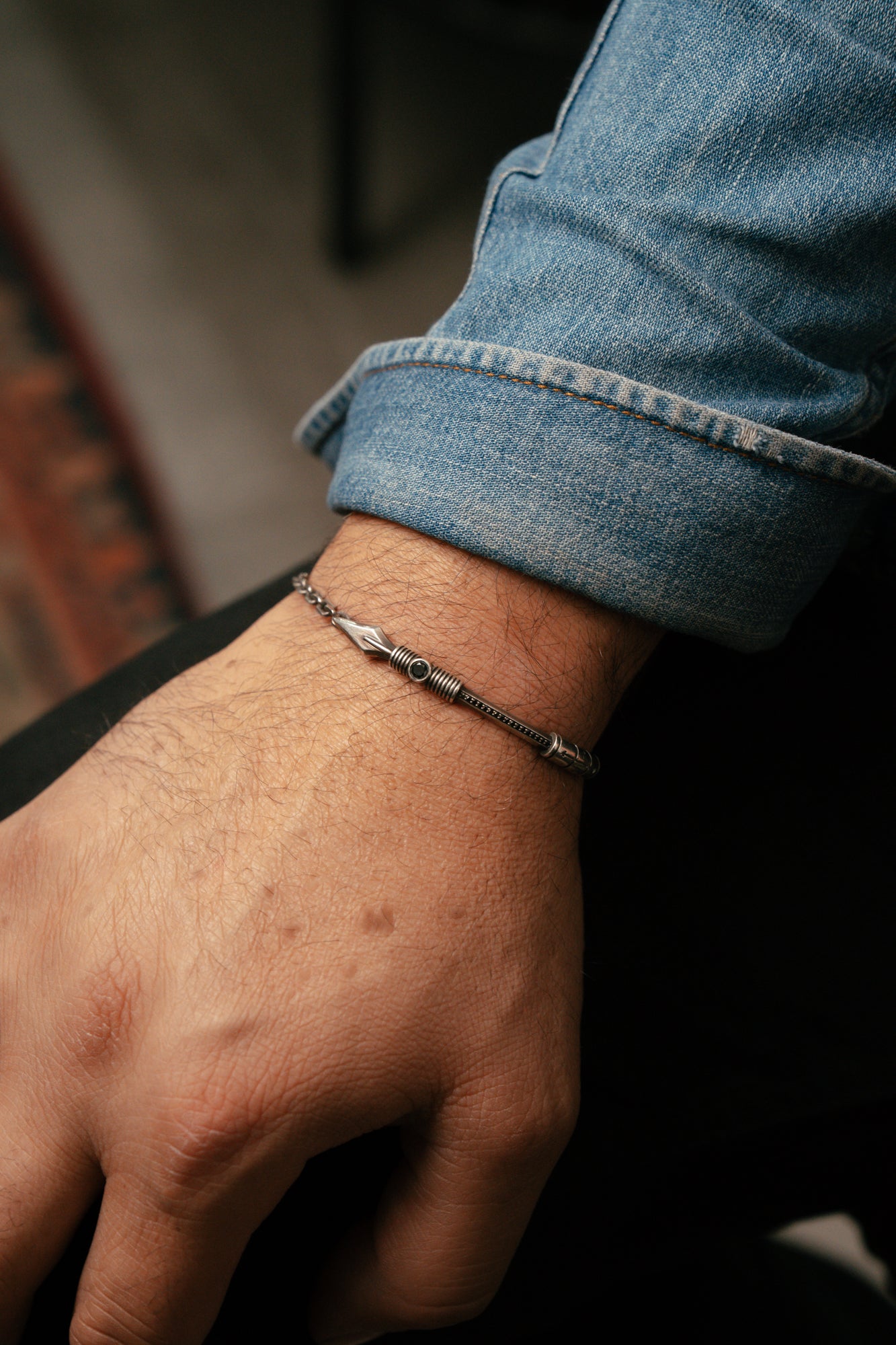 Close-up of a hand wearing a silver bracelet with a blurred background