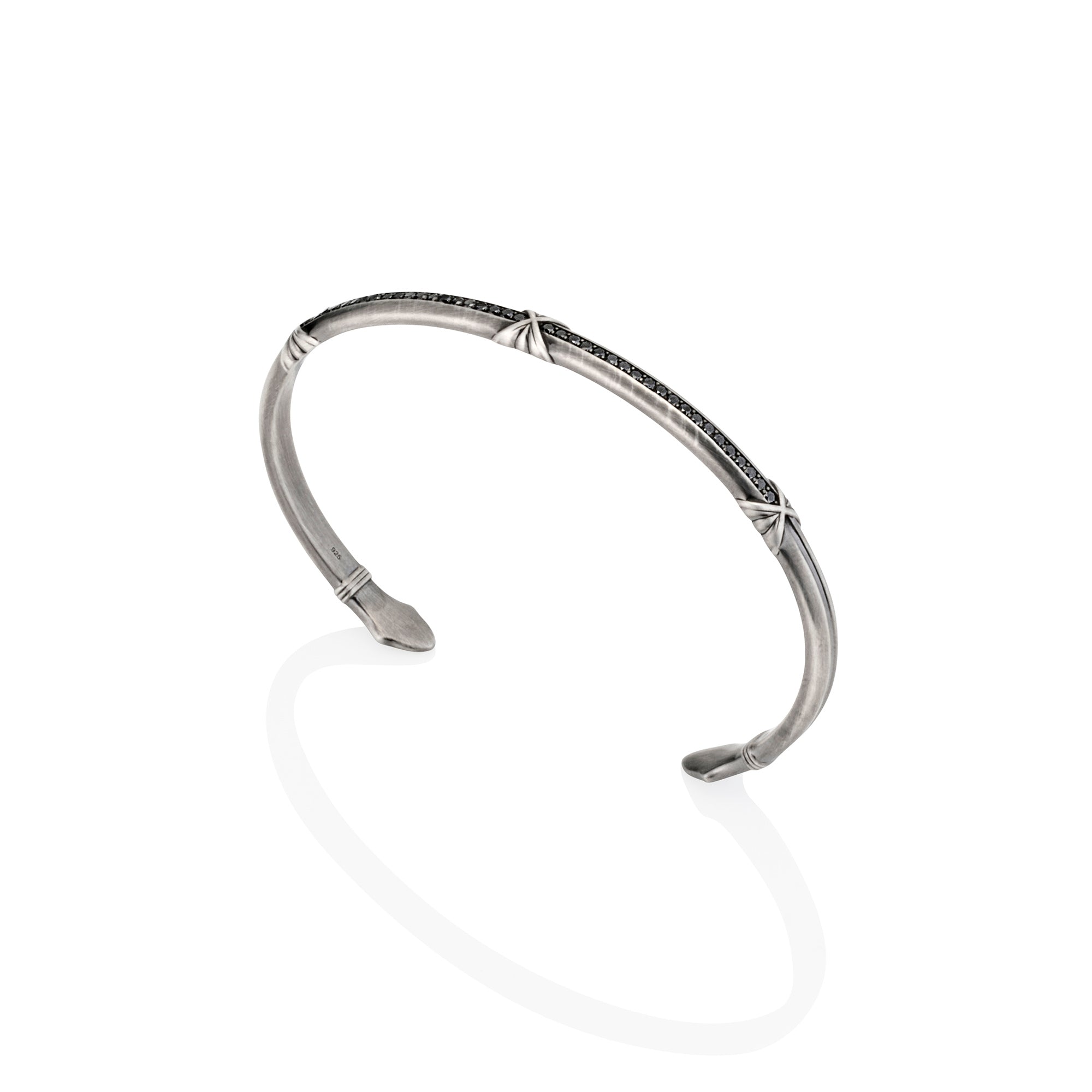 Silver oxidised cuff with black diamonds with arrow-shaped ends on a white background.