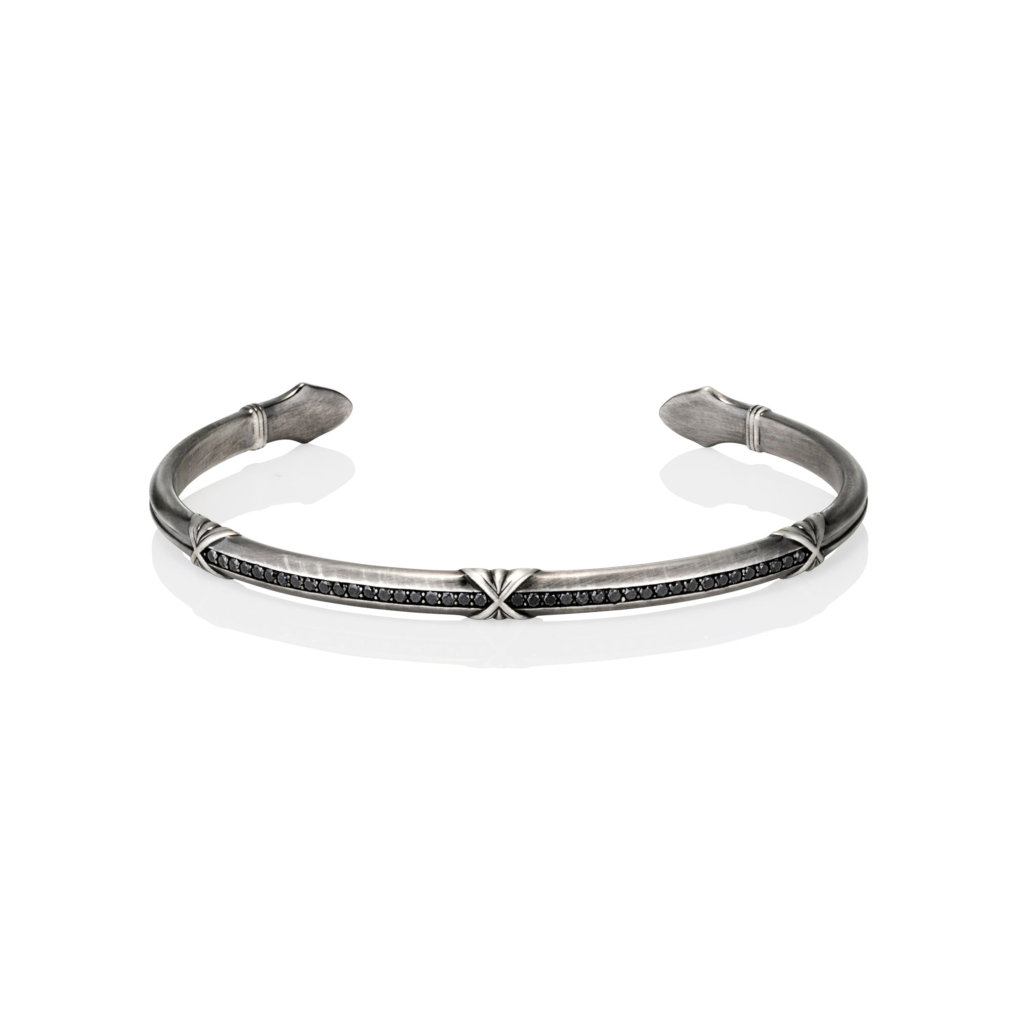 Silver oxidised cuff with black diamonds with arrow-shaped ends on a white background.