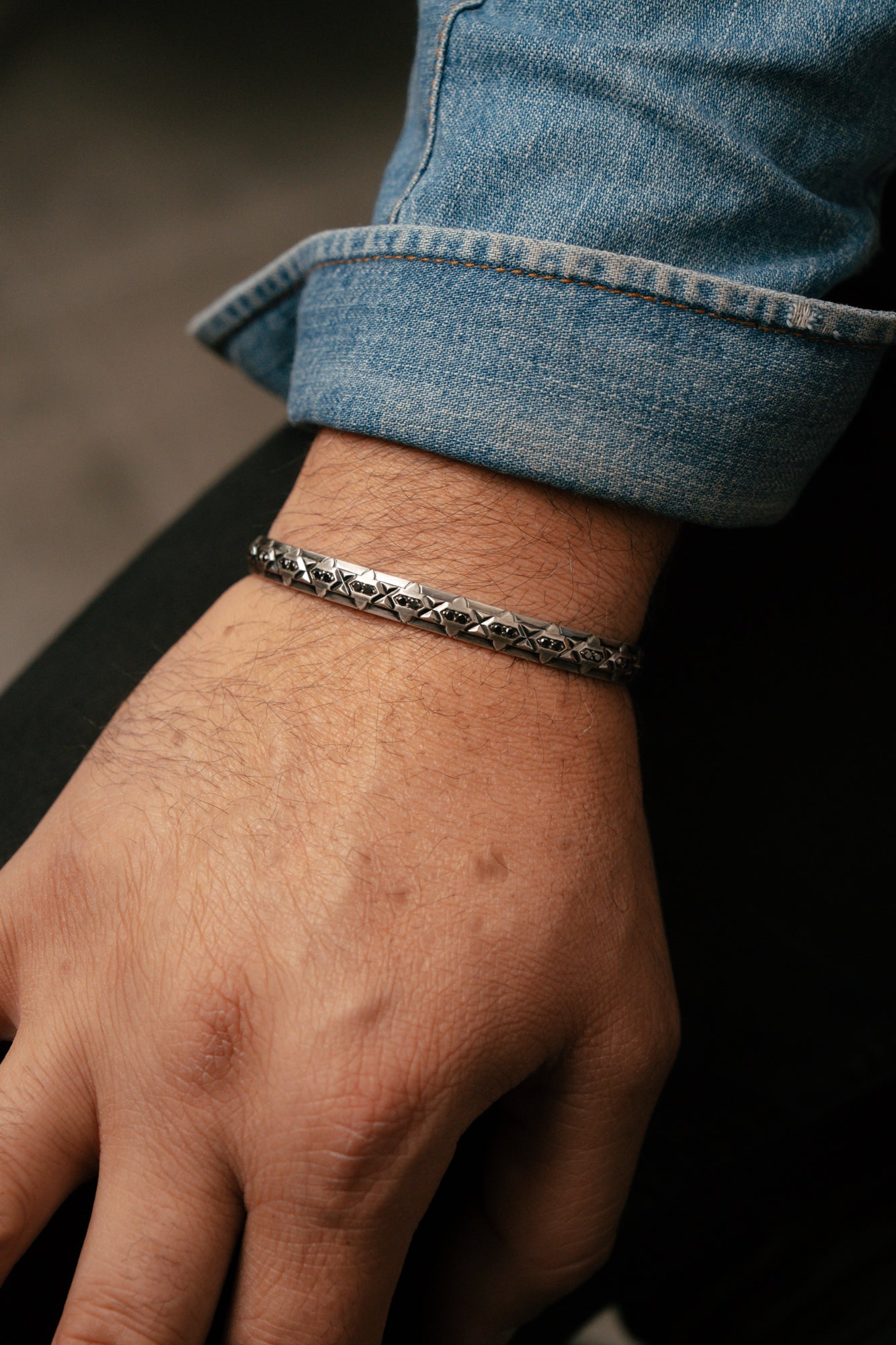Close-up of a wrist wearing a silver bracelet with a blurred background