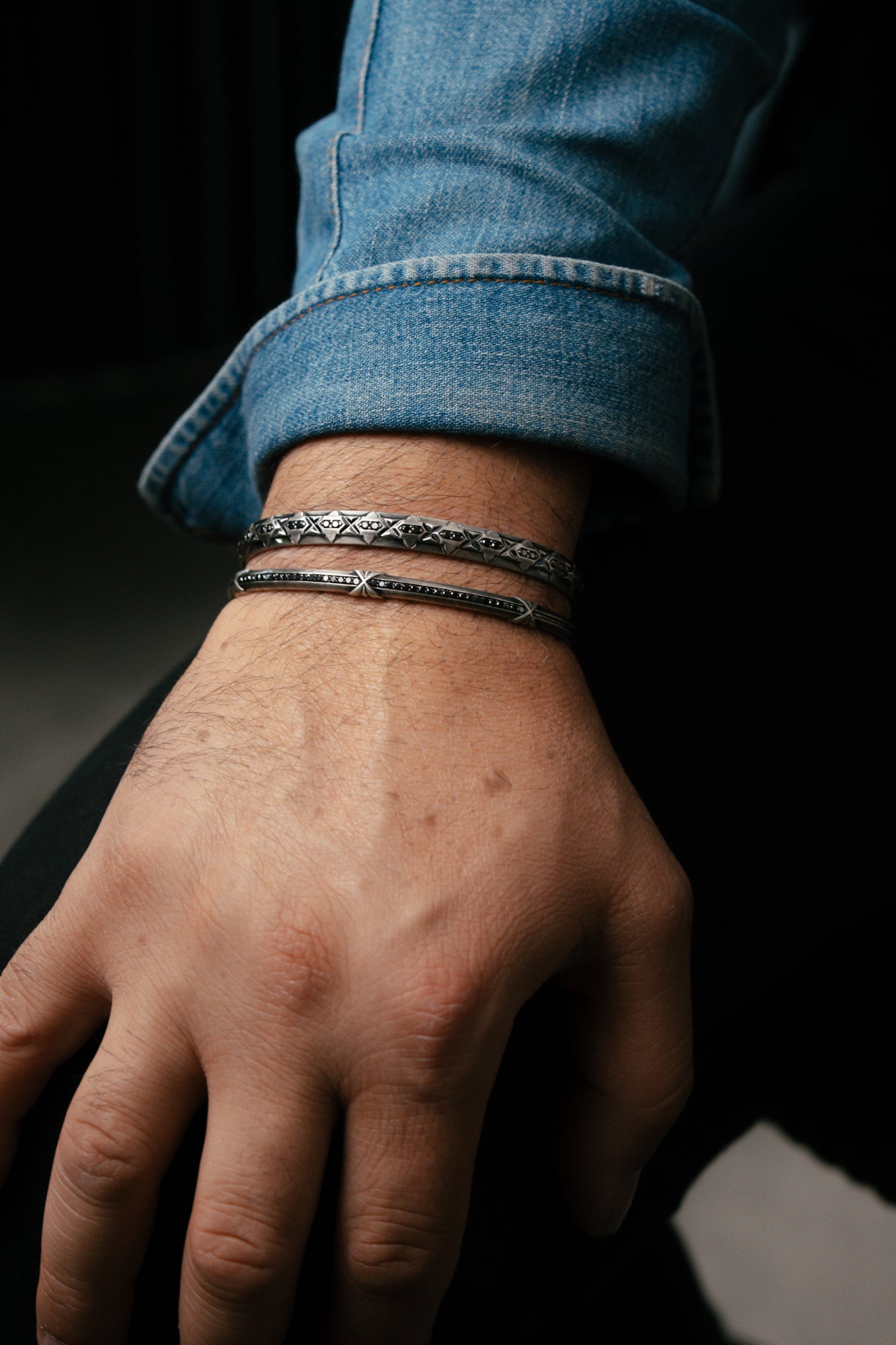 Hand wearing a bracelet stack with a dark background