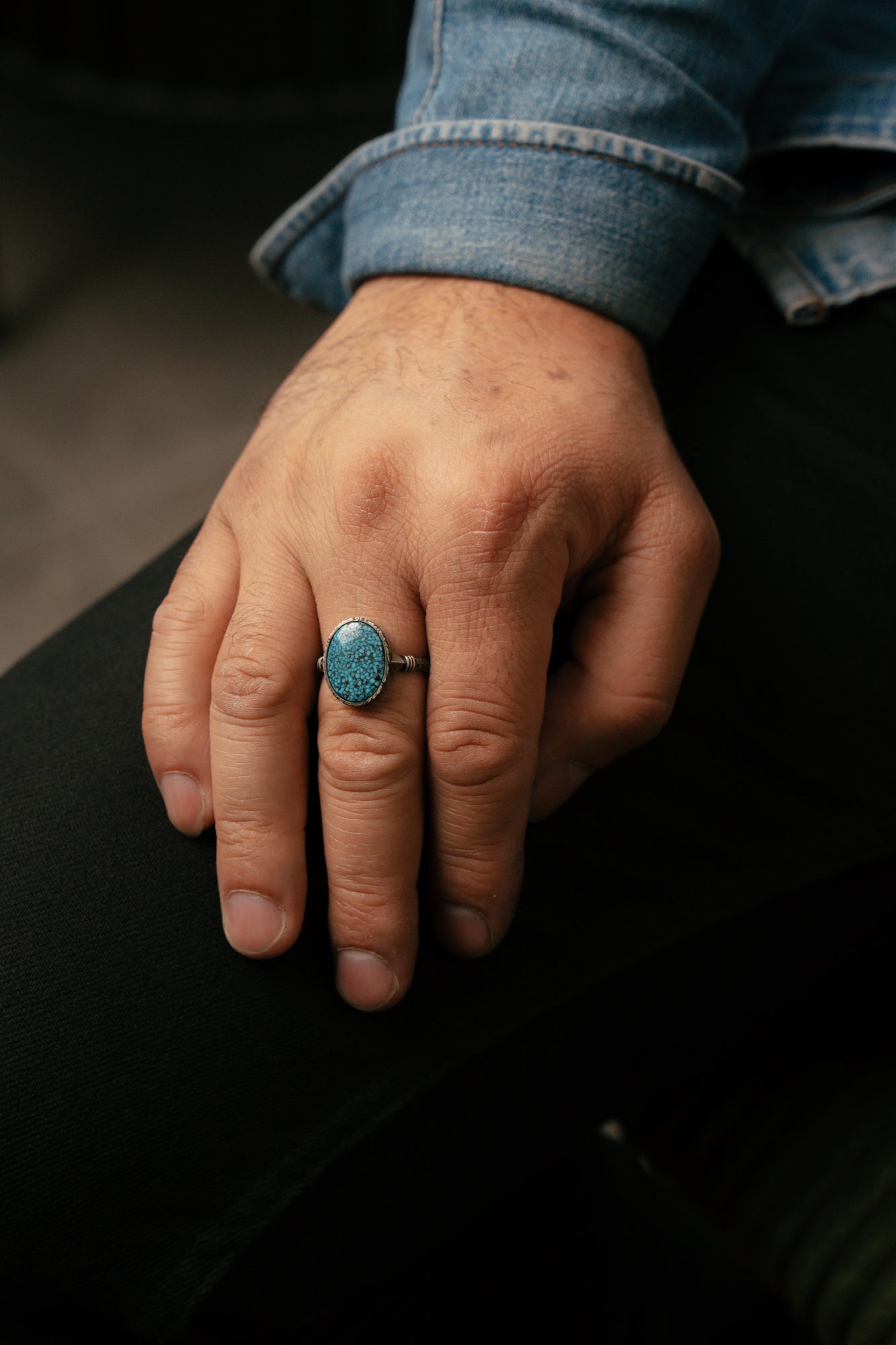 Hand wearing a turquoise ring with a blurred background