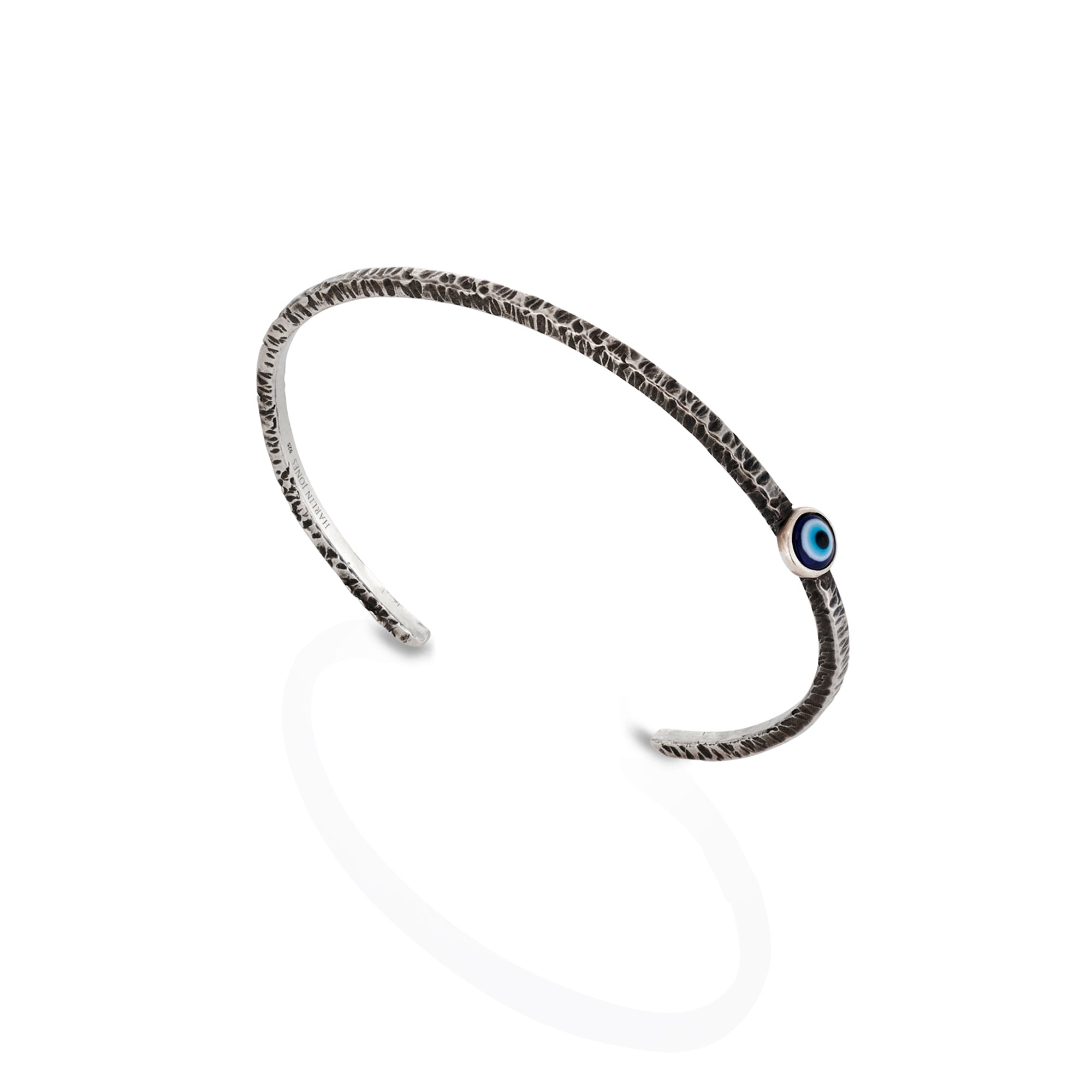 Silver bracelet with a blue evil eye gemstone on a white background