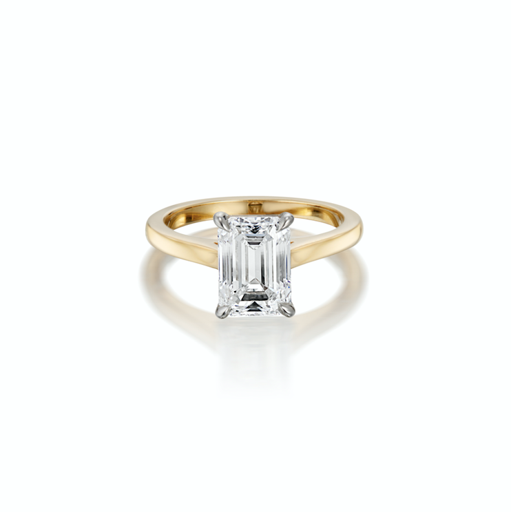 Gold ring with a single emerald-cut diamond, against a white background.