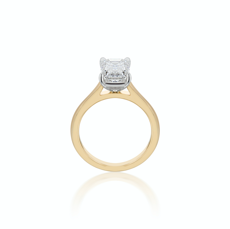 Gold engagement ring with a single large emerald cut diamond, isolated on a white background.