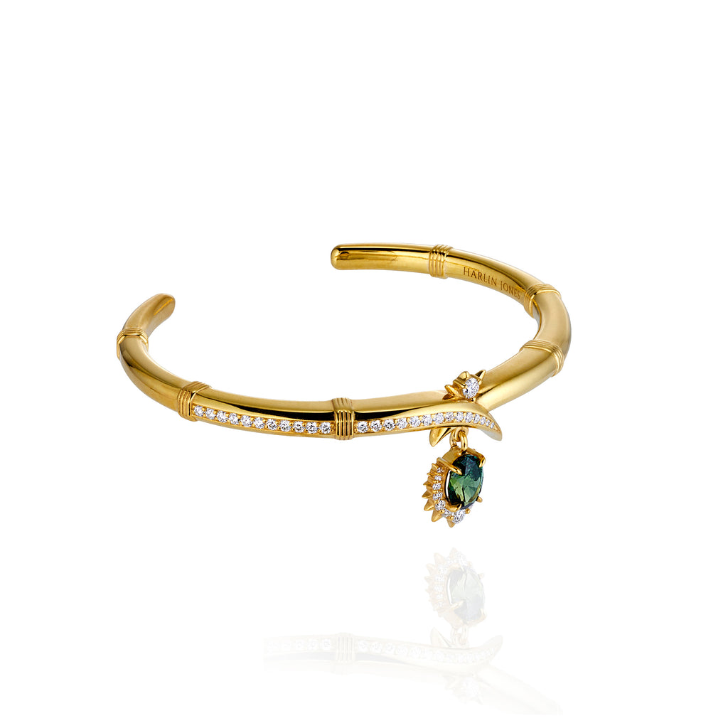 Elegant gold bracelet showcasing a central green stone, embellished with sparkling diamonds on the sides.
