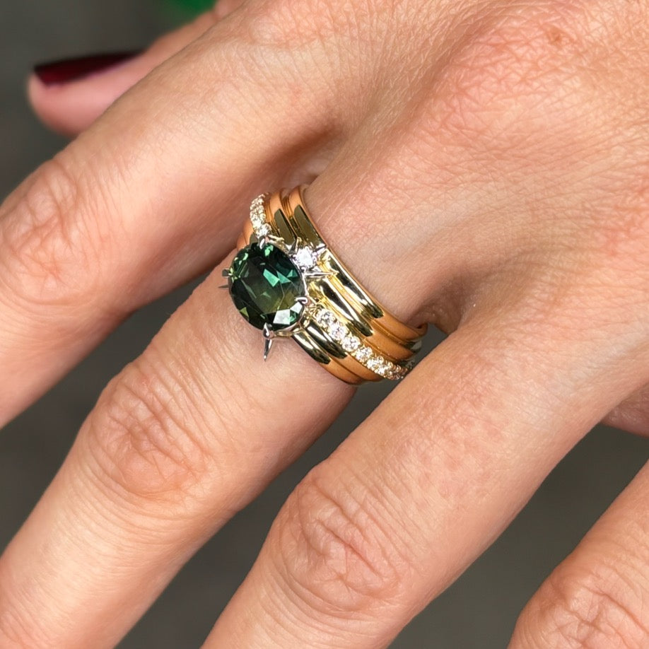 Yellow gold band with centred green Australian parti sapphire and diamonds on finger