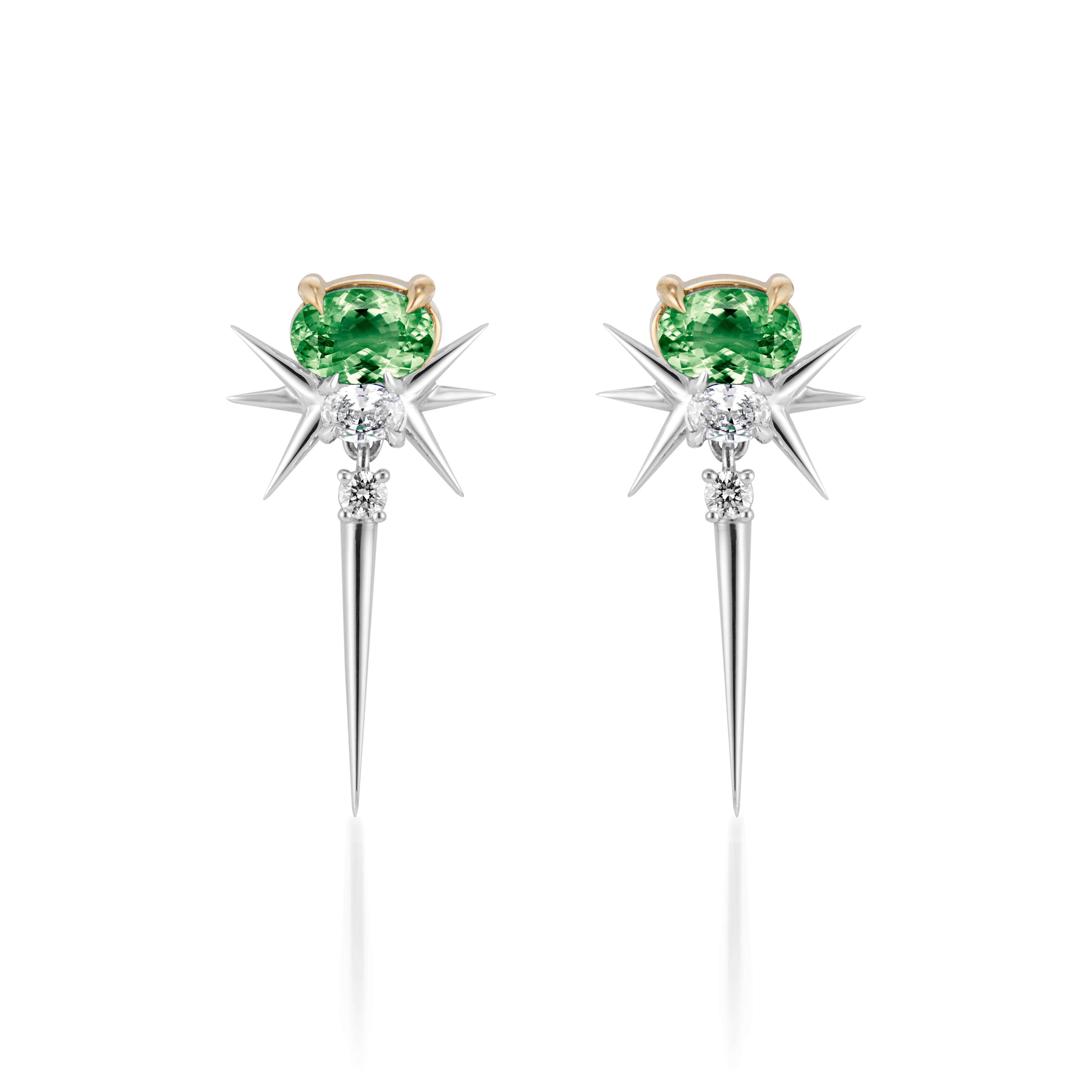 earrings feature a unique design with a central green gemstone—likely a tourmaline or similar stone—set in a gold or light-colored metal prong. The earrings are accented by elongated, pointed spikes that create a starburst effect, enhancing their dramatic look. The combination of colored stones and metallic elements makes them stand out as a statement piece.
