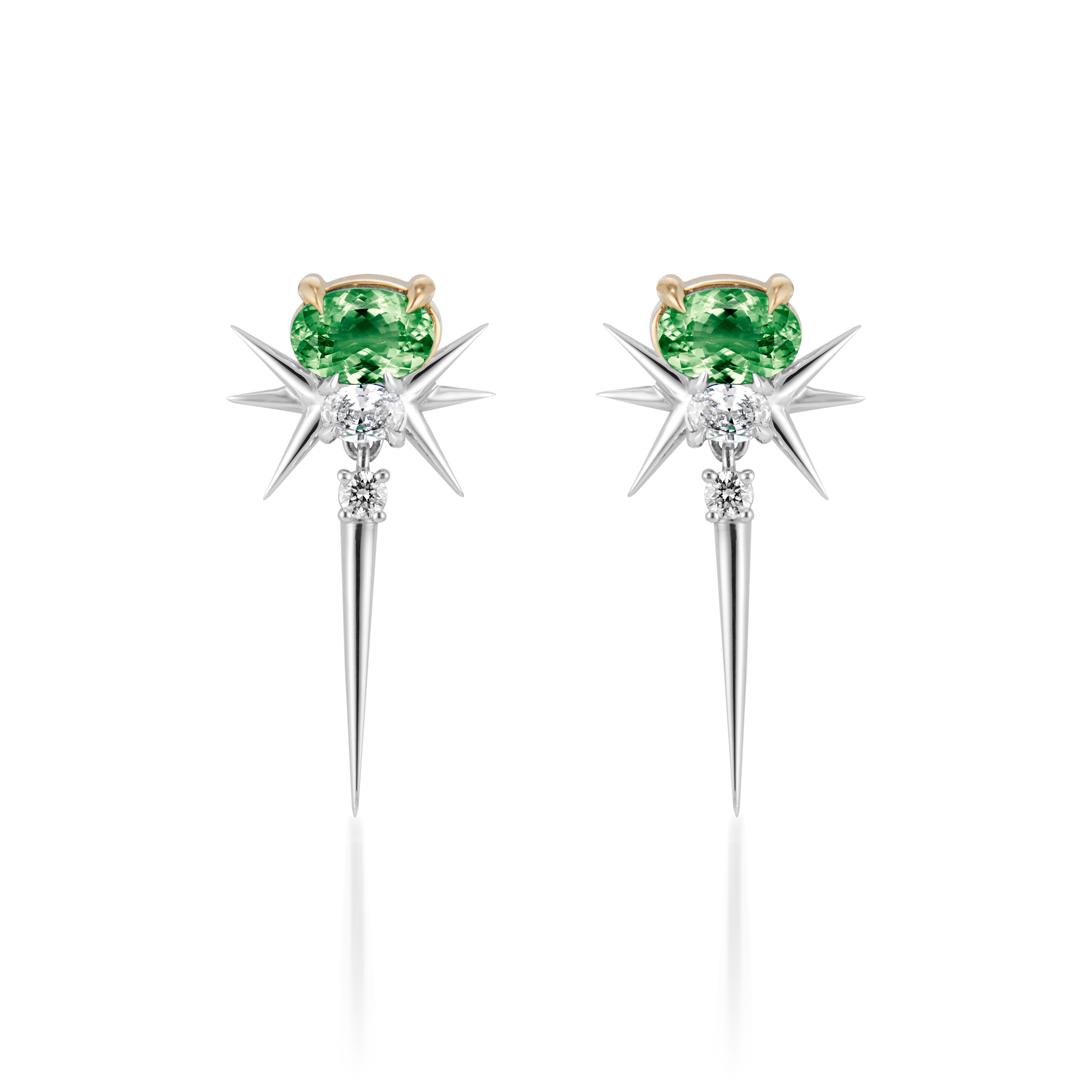 earrings feature a unique design with a central green gemstone—likely a tourmaline or similar stone—set in a gold or light-colored metal prong. The earrings are accented by elongated, pointed spikes that create a starburst effect, enhancing their dramatic look. The combination of colored stones and metallic elements makes them stand out as a statement piece.