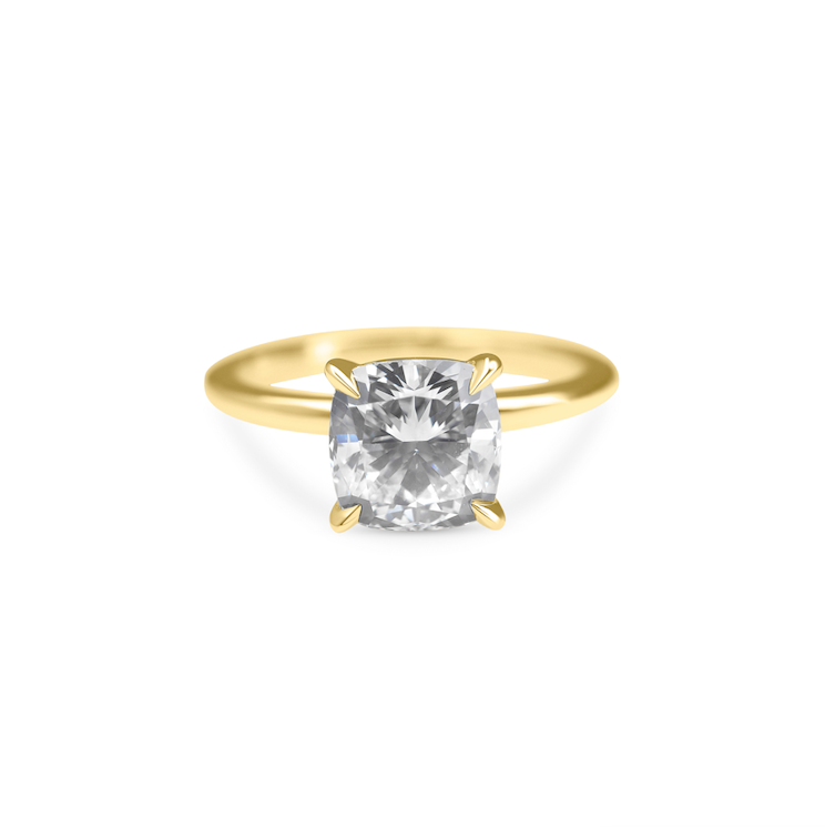 Gold band ring with a large, central, cushion-cut diamond. On white background 