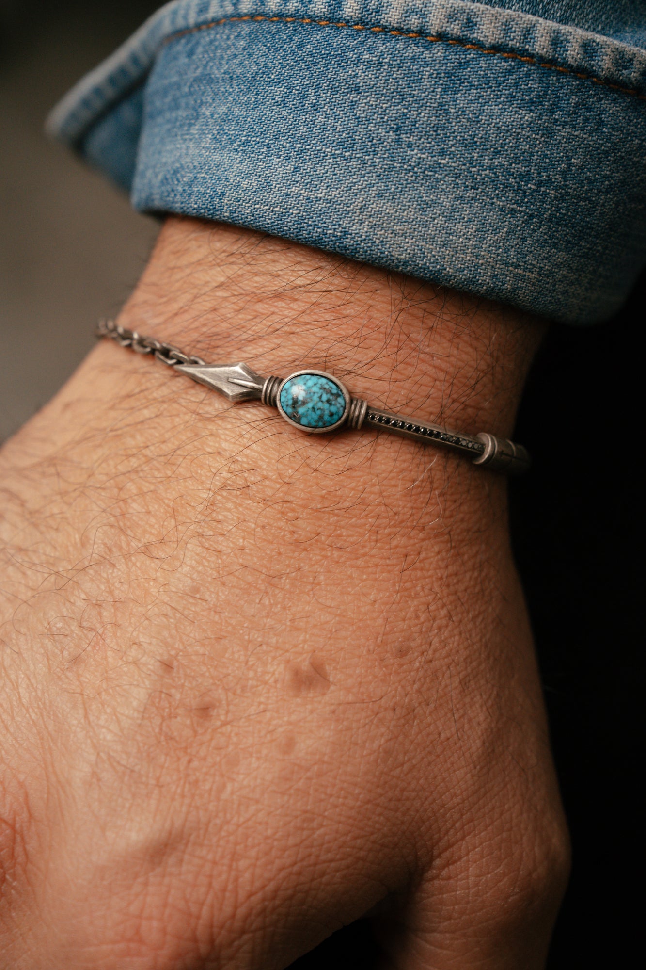 Bracelet with turquoise stone on a wrist, wearing blue jeans
