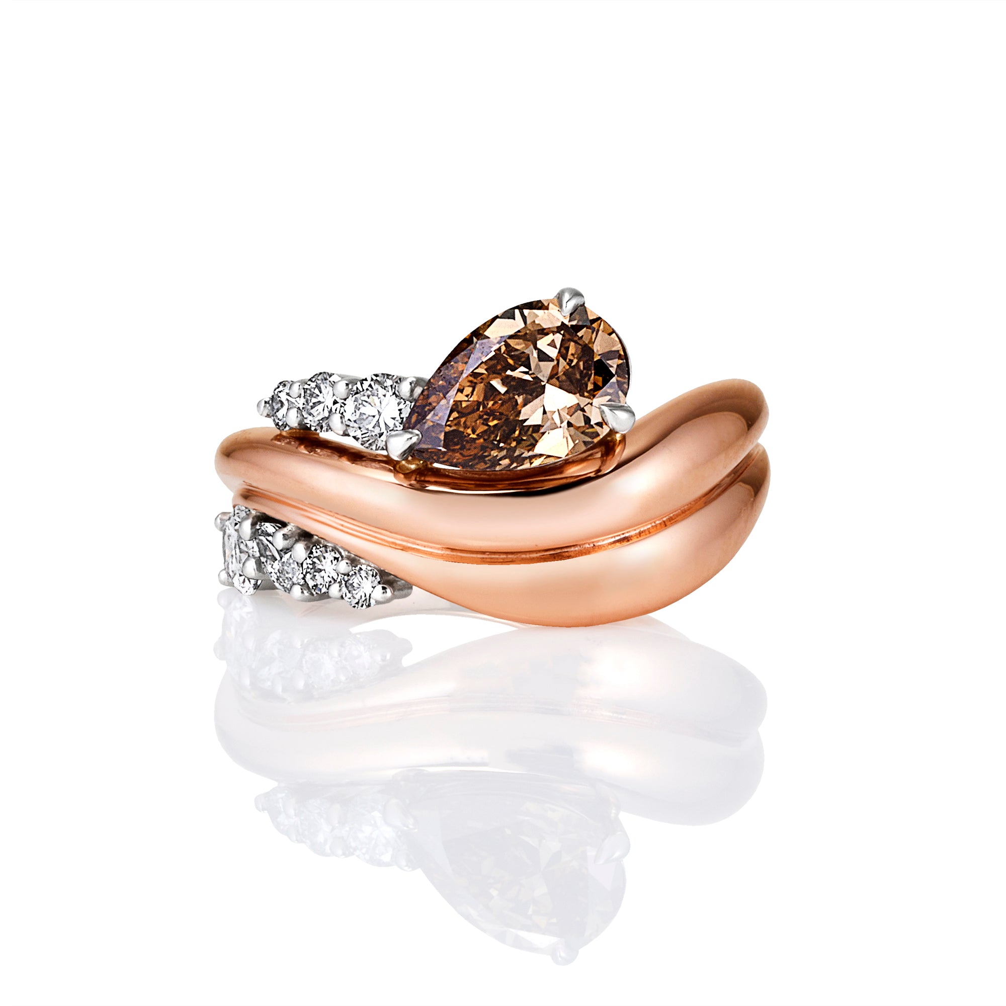 A rose gold ring with a large pear-cut brown gemstone and diamond accents, displayed on a clean white background with a soft reflection.