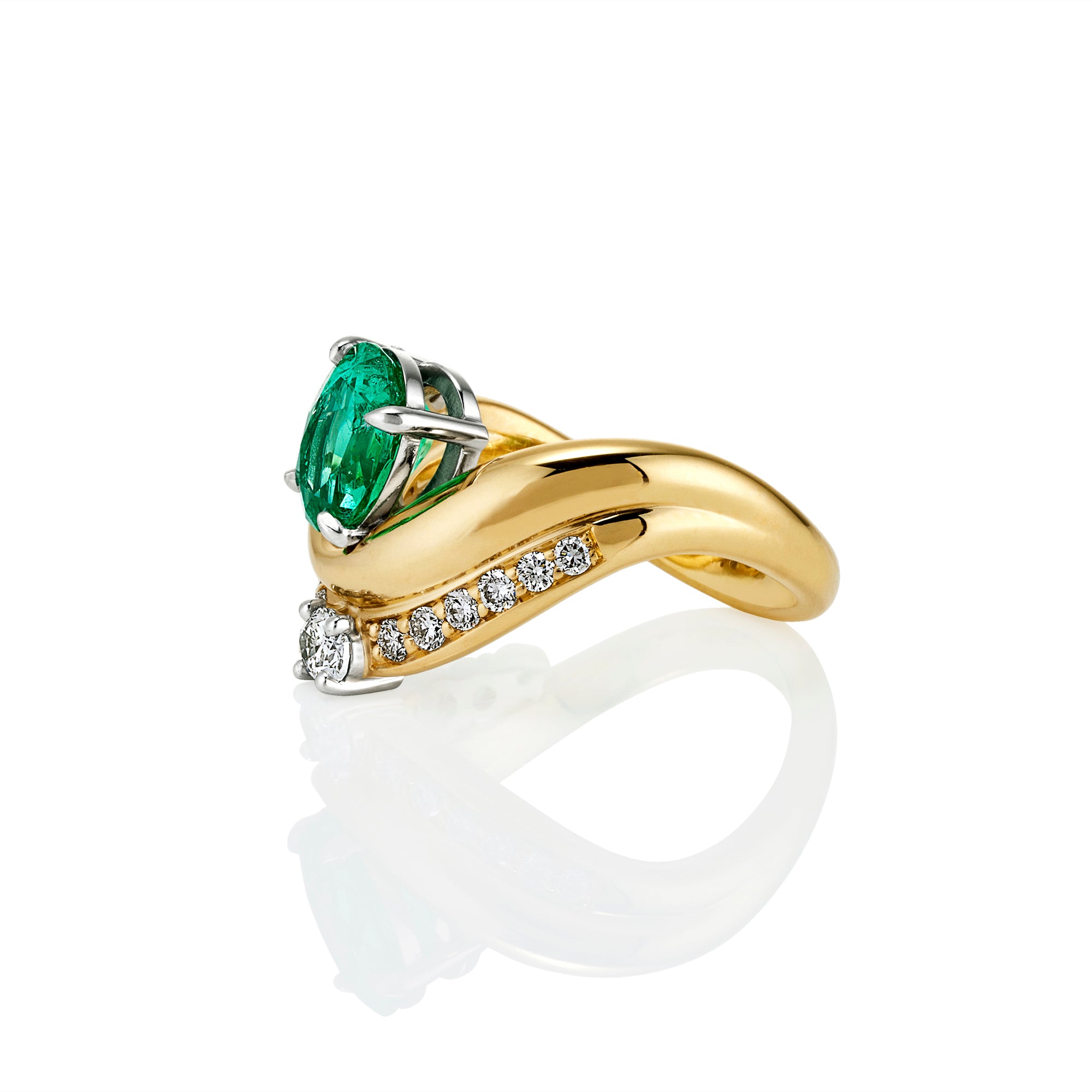 A yellow gold ring with a large oval-cut green emerald gemstone, accented by small pavé-set clear stones along the band, shown on a white background with a soft reflection.