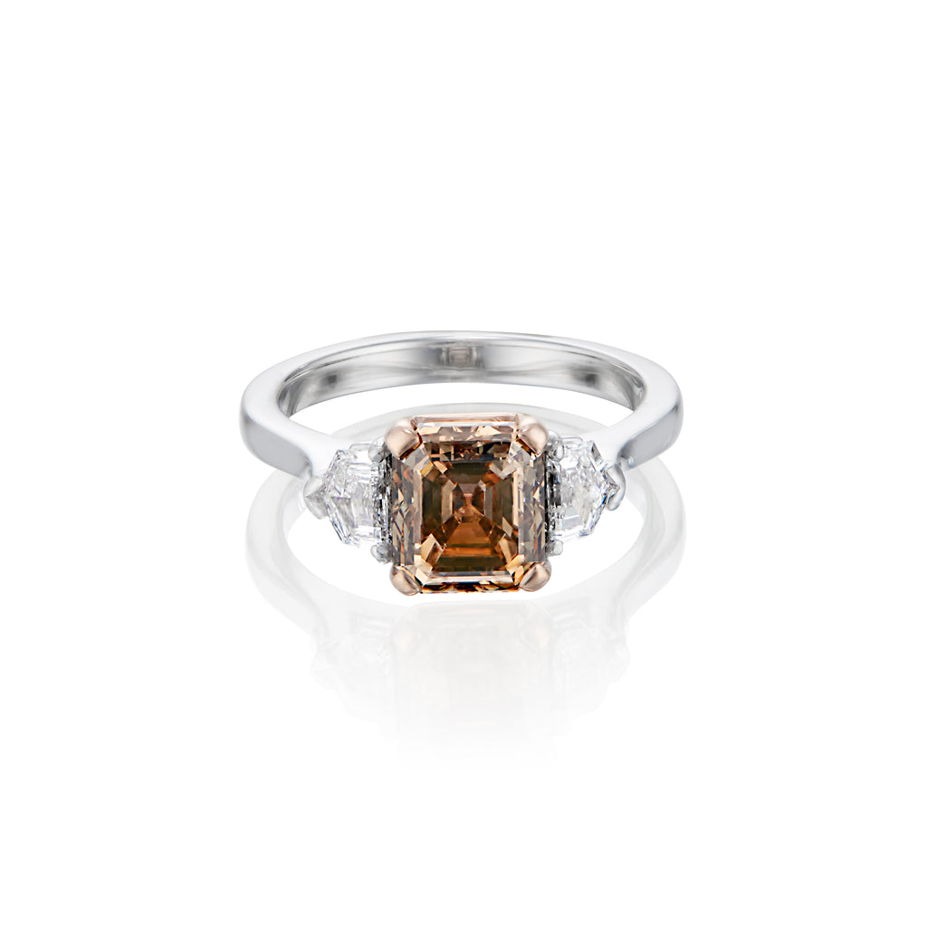 White gold ring with a central Asscher cut champagne diamond flanked by two smaller white diamonds.