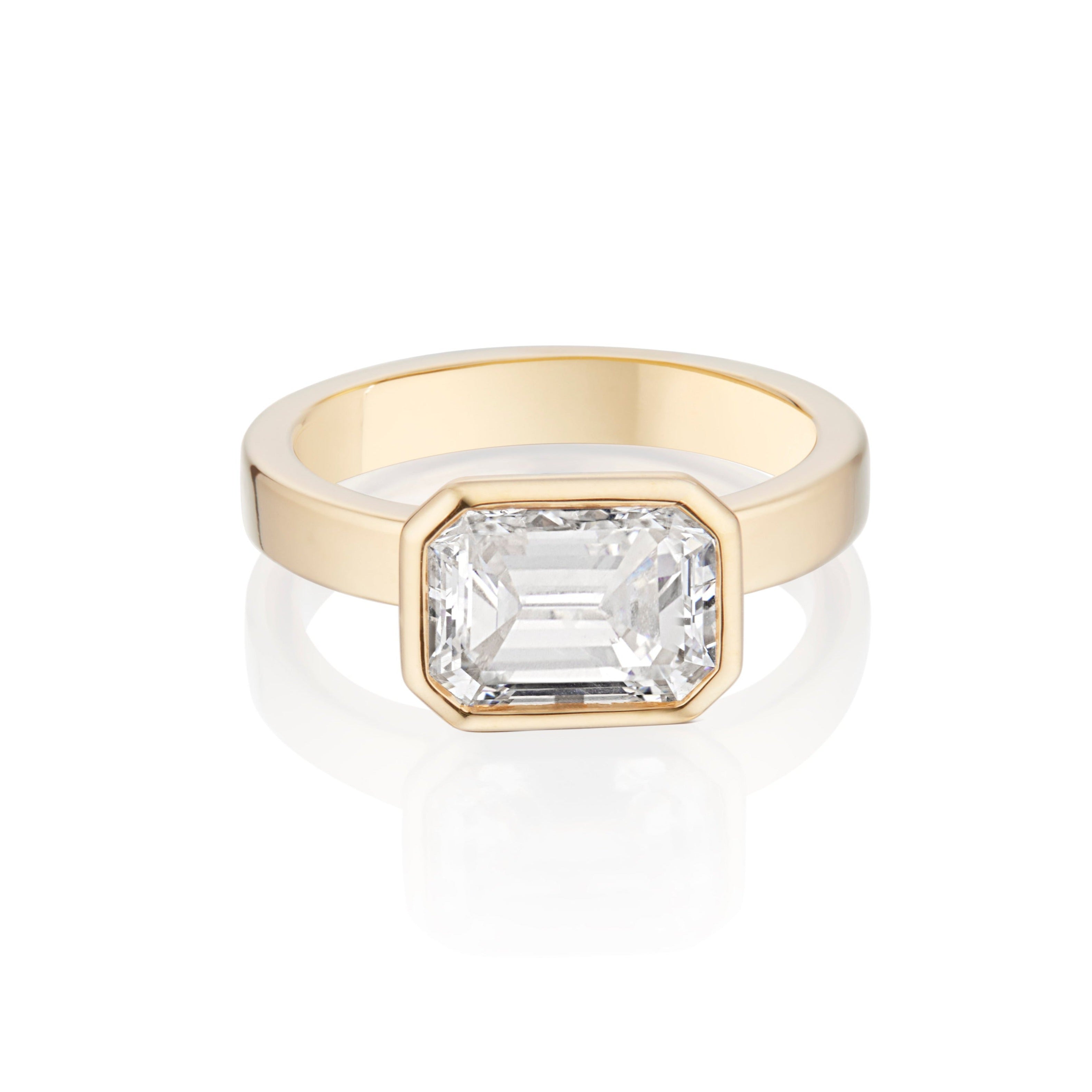 Gold ring with a single Emerald Cut diamond, on a white background.