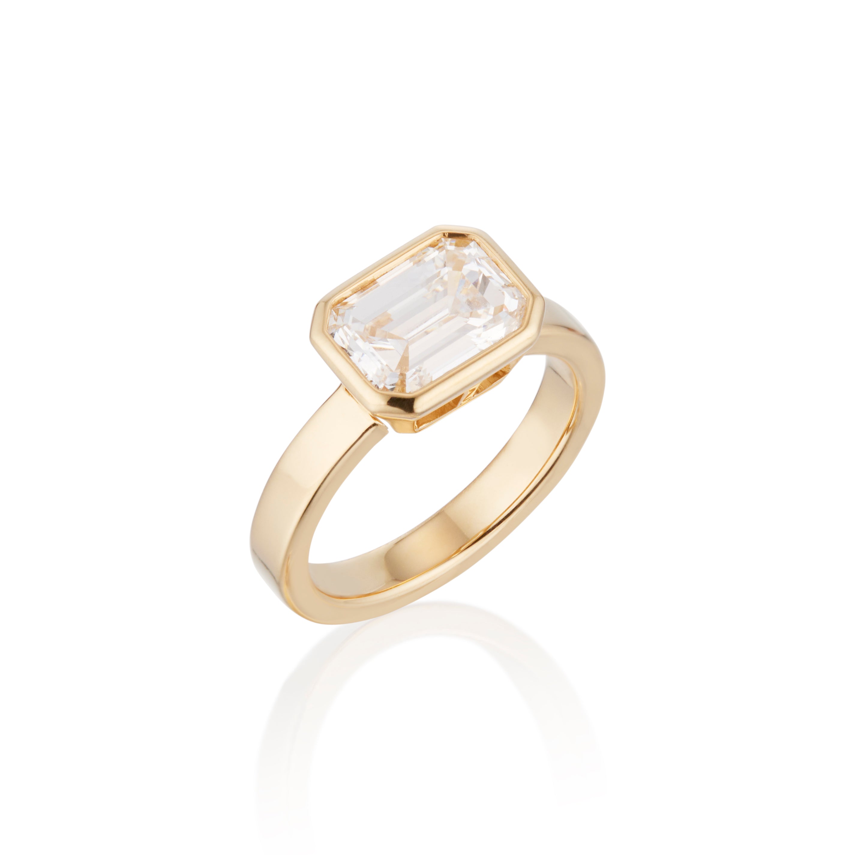 Gold ring with a emerald cut diamond solitaire on a white background.