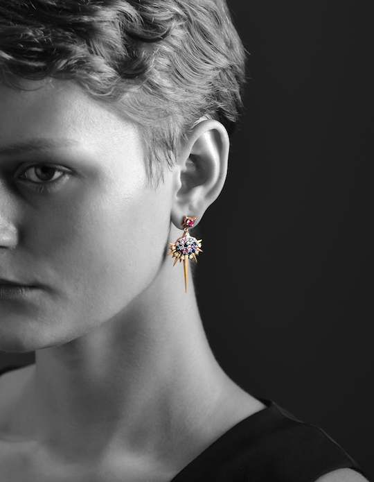Black and white photo of a person with a colorful earring, viewed from the side.