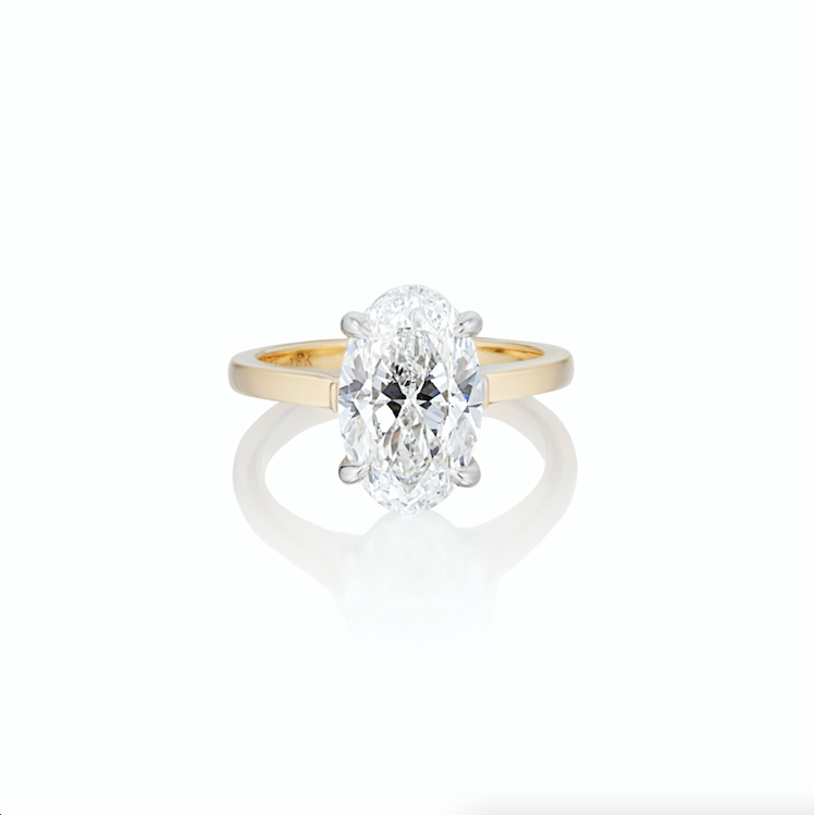 Oval solitaire diamond engagement ring with a gold band on a white background.