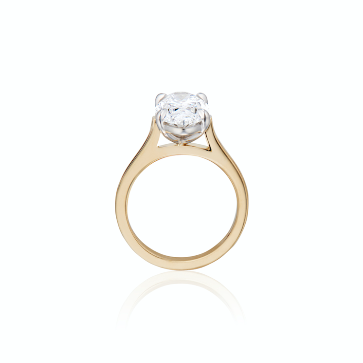 Solitaire diamond engagement ring in gold setting on white background.