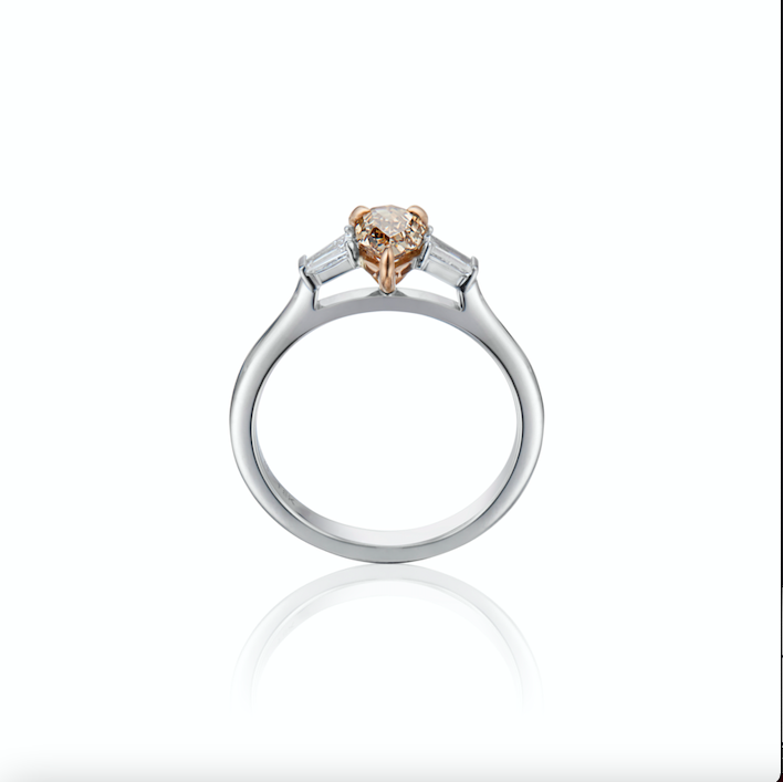 An elegant ring with a central Champagne diamond flanked by two smaller baguette diamonds, on a white background.