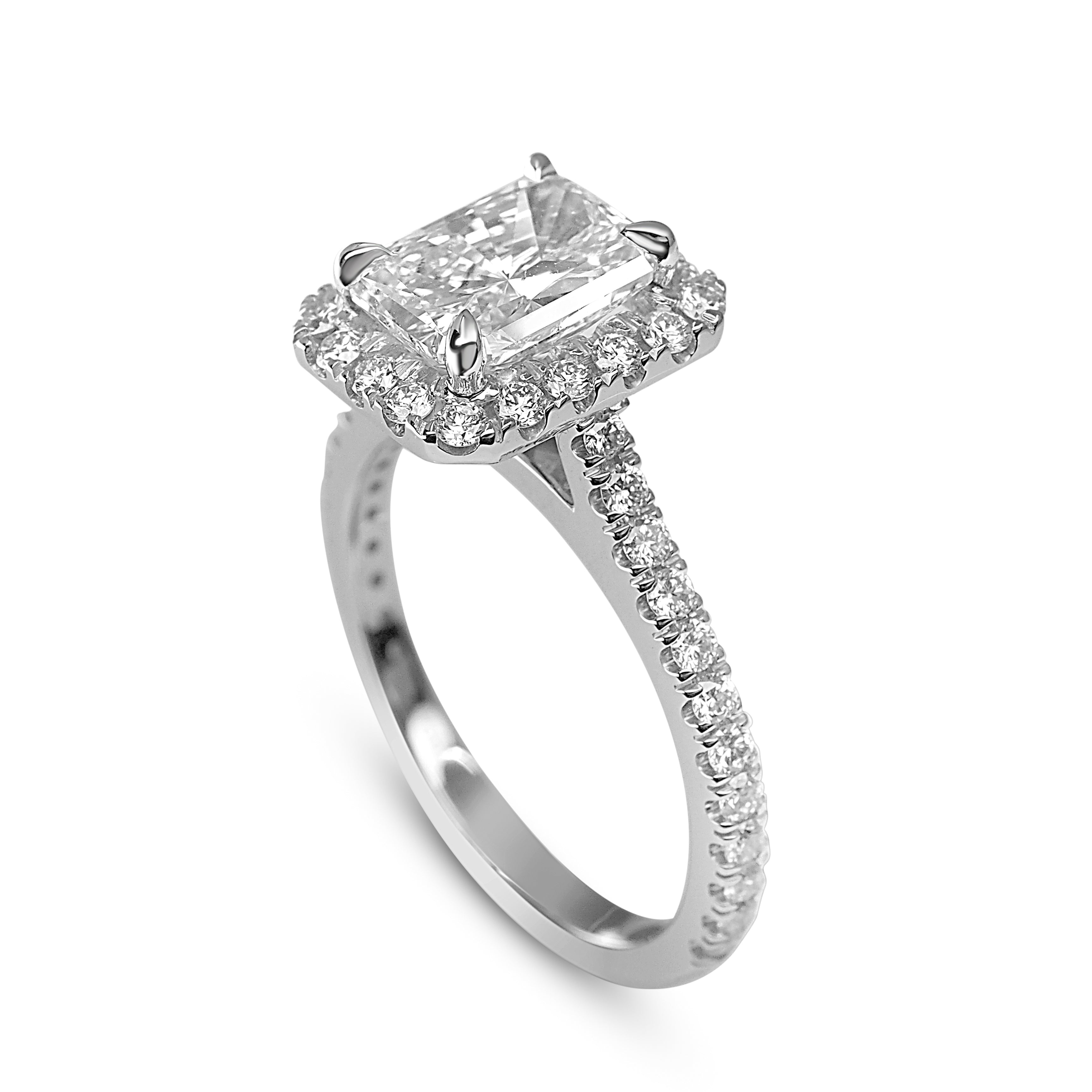White gold ring with a large radiant-cut diamond surrounded by smaller diamonds on a thin band.