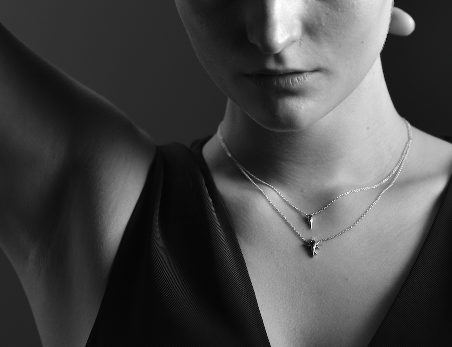 Black and white image of a person's neck with a star pendant necklace.