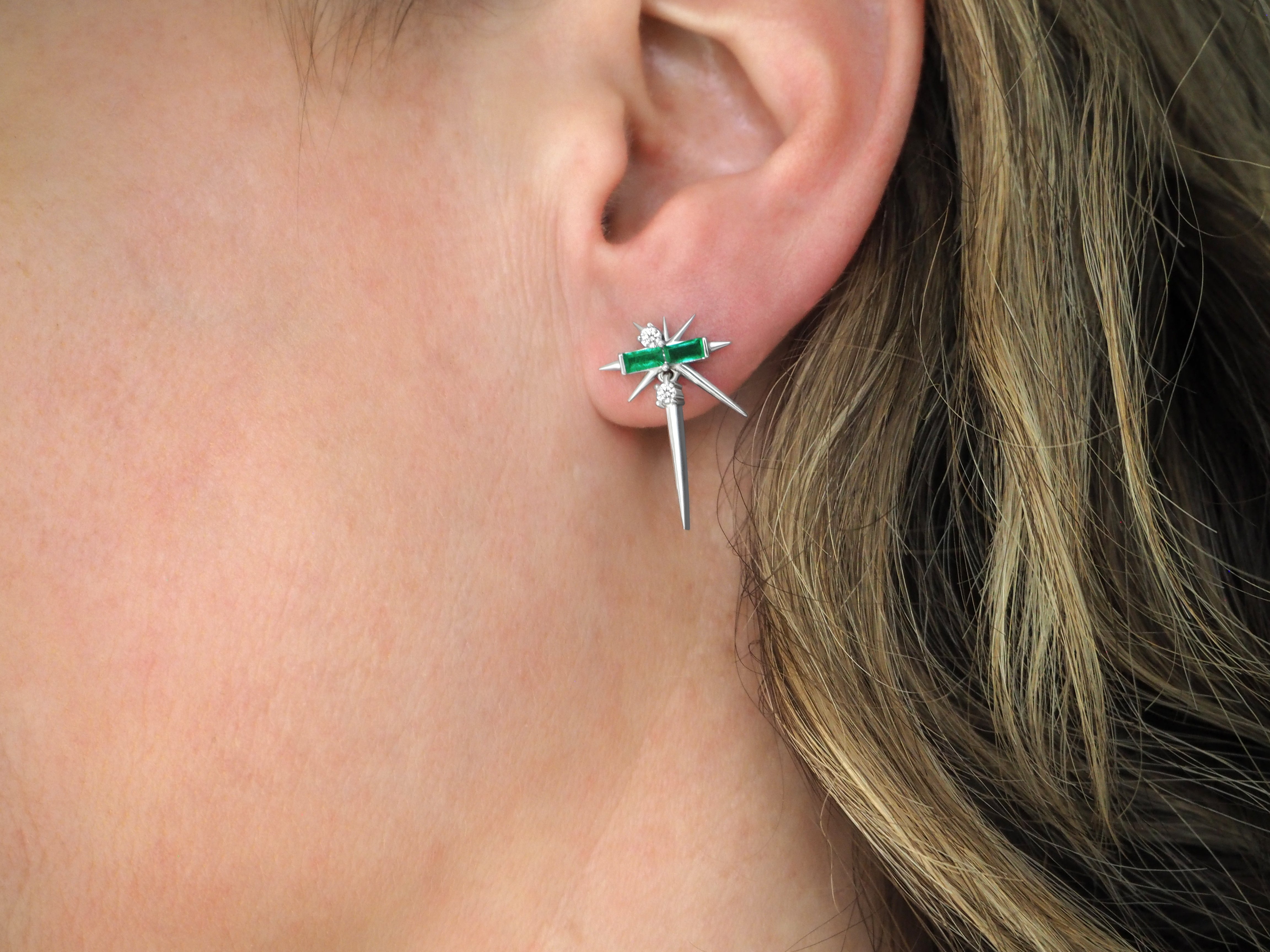 Close-up of a person's ear wearing a green and silver dragonfly earring.