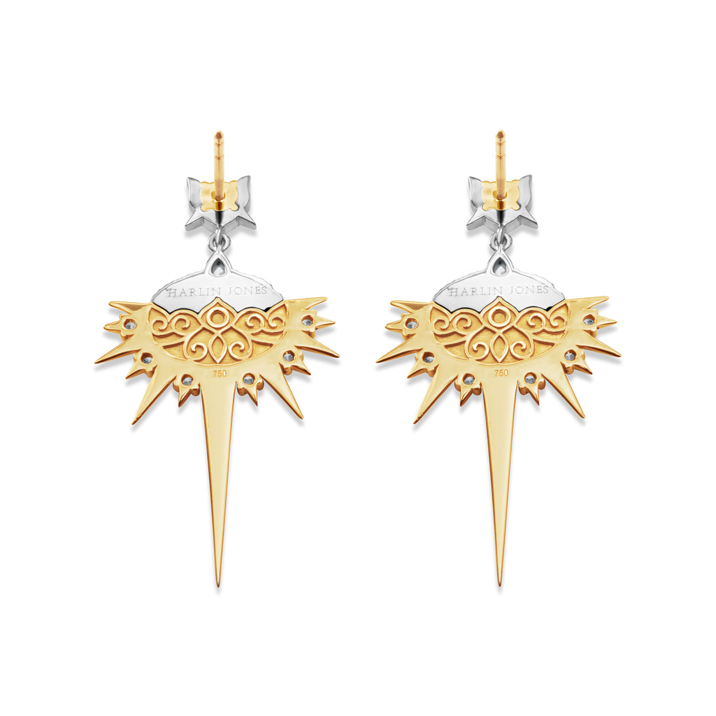 Back view of Sapphire Drop Earrings. Earring post is yellow gold and fixed to a white gold stud. From here, the earring drop is suspended by a single chain link of white gold. The top section of the oval design is white gold with an engraved logo that reads Harlin Jones. Below the white gold is a yellow gold filigree detail. Yellow gold spikes extend outwards from the edge of the oval with an extra-long spike at the bottom center.