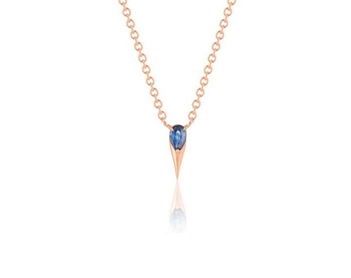   Front view of unique blue sapphire pendant necklace connected to a rose gold round-link chain by 2 angled rose gold prongs. The pear-shaped blue sapphire stone is set at the top of a rose gold spike that drops below, forming a water droplet shape. 
