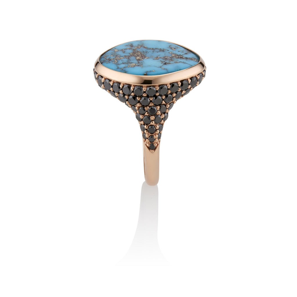 Shank view. Rose gold and turquoise ring. The pave-set black diamond encrusted design follows the ring’s tapered shape. The turquoise stone is framed by a thick band of rose gold that lays flat along the top edge, flush with the stone.
