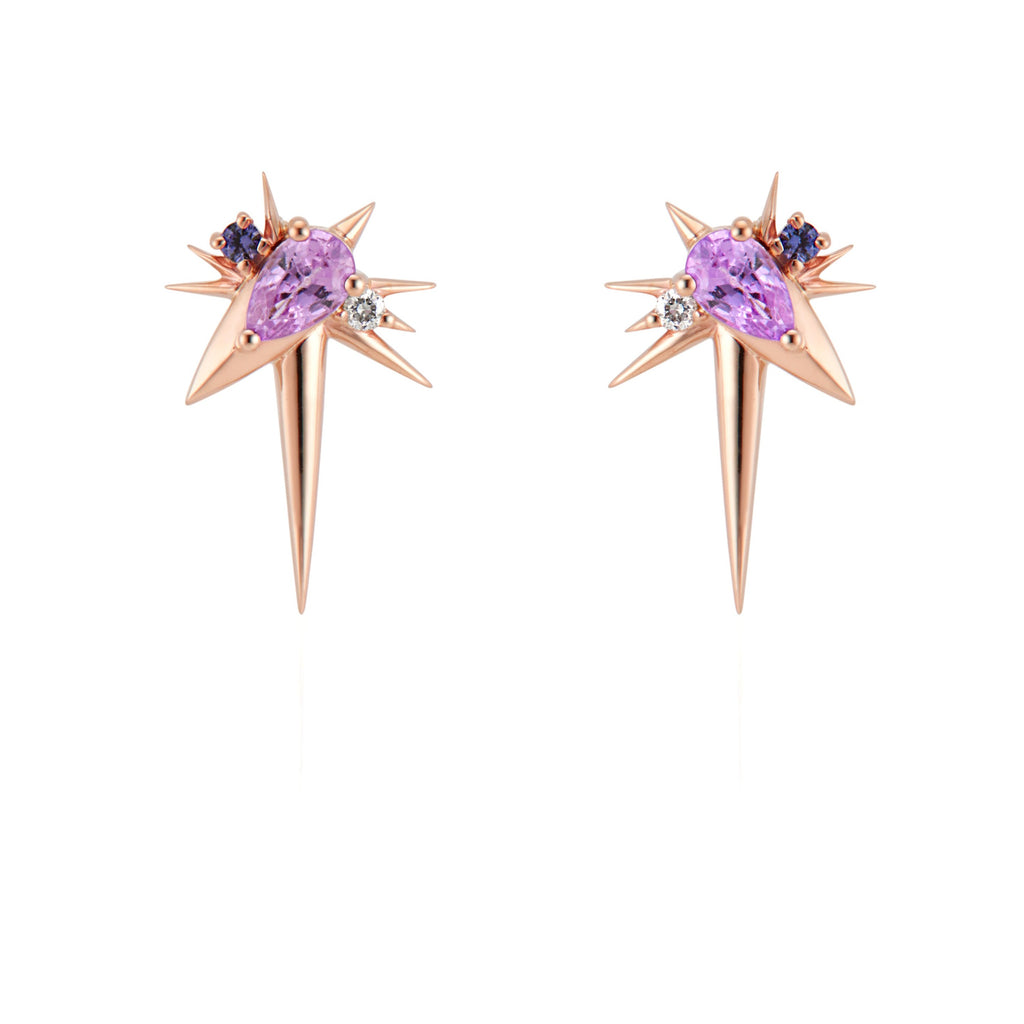  Front view of slanted drop earrings, each with 1 pear-shaped pink sapphire, set at 45-degree angle, flanked by small round diamonds and sapphires. 9 rose gold spikes of varying lengths extend from the oval setting, with a larger and longer spike pointed down. 
