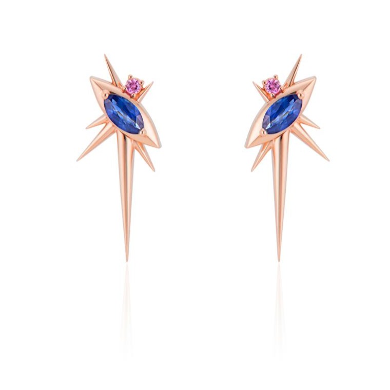 Front view of alternative drop earrings, each with 1 marquise-shaped blue sapphire, set at a 45-degree angle, with a small pink sapphire above. 6 rose gold spikes of varying lengths extend from the setting, with a large, long spike pointed down. 