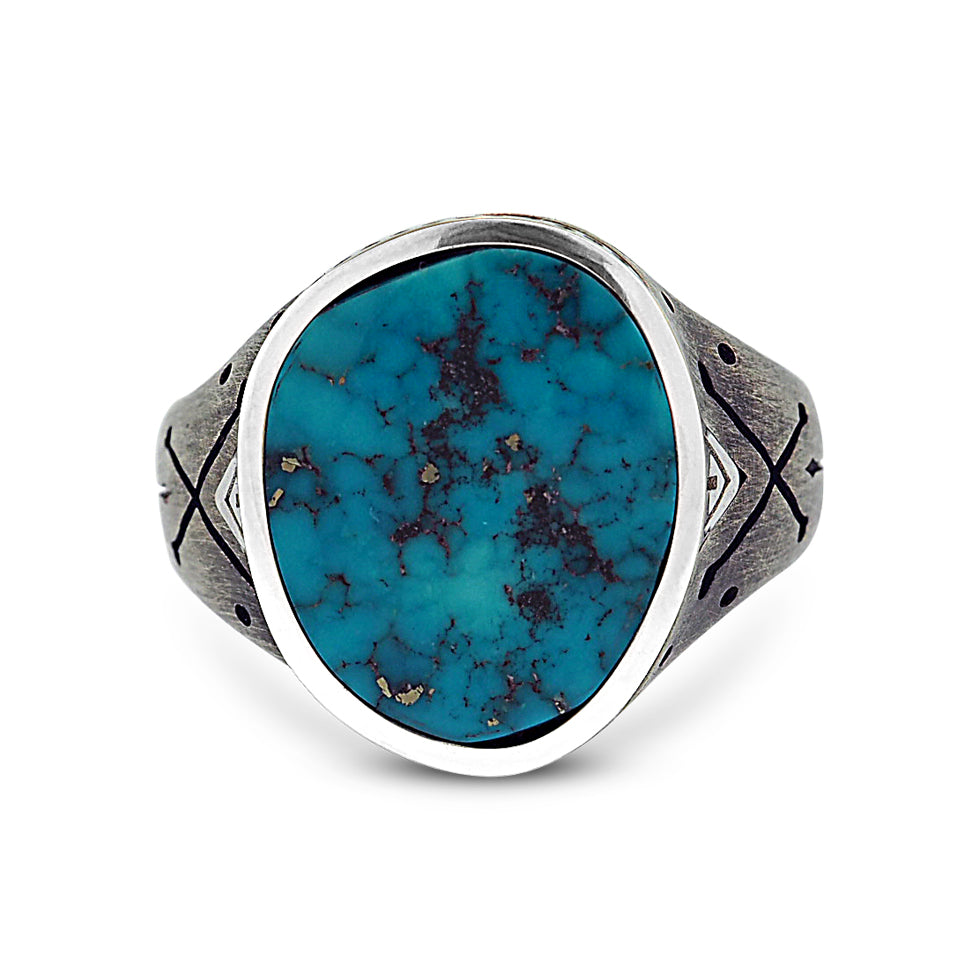 Bespoke jewelry piece from New York. Turquoise Cross-Bones ring with polished sterling silver setting and oxidized sterling silver band. The setting has a freeform oval shape with a handset Morenci turquoise stone with spider-web configurations of iron pyrite. On either side of the setting, there are polished sterling silver triangles that point to the hand-engraved cross-bones on the band.