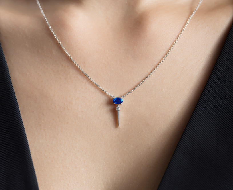 Close-up of a white gold chain necklace on a person wearing a dark jacket.
