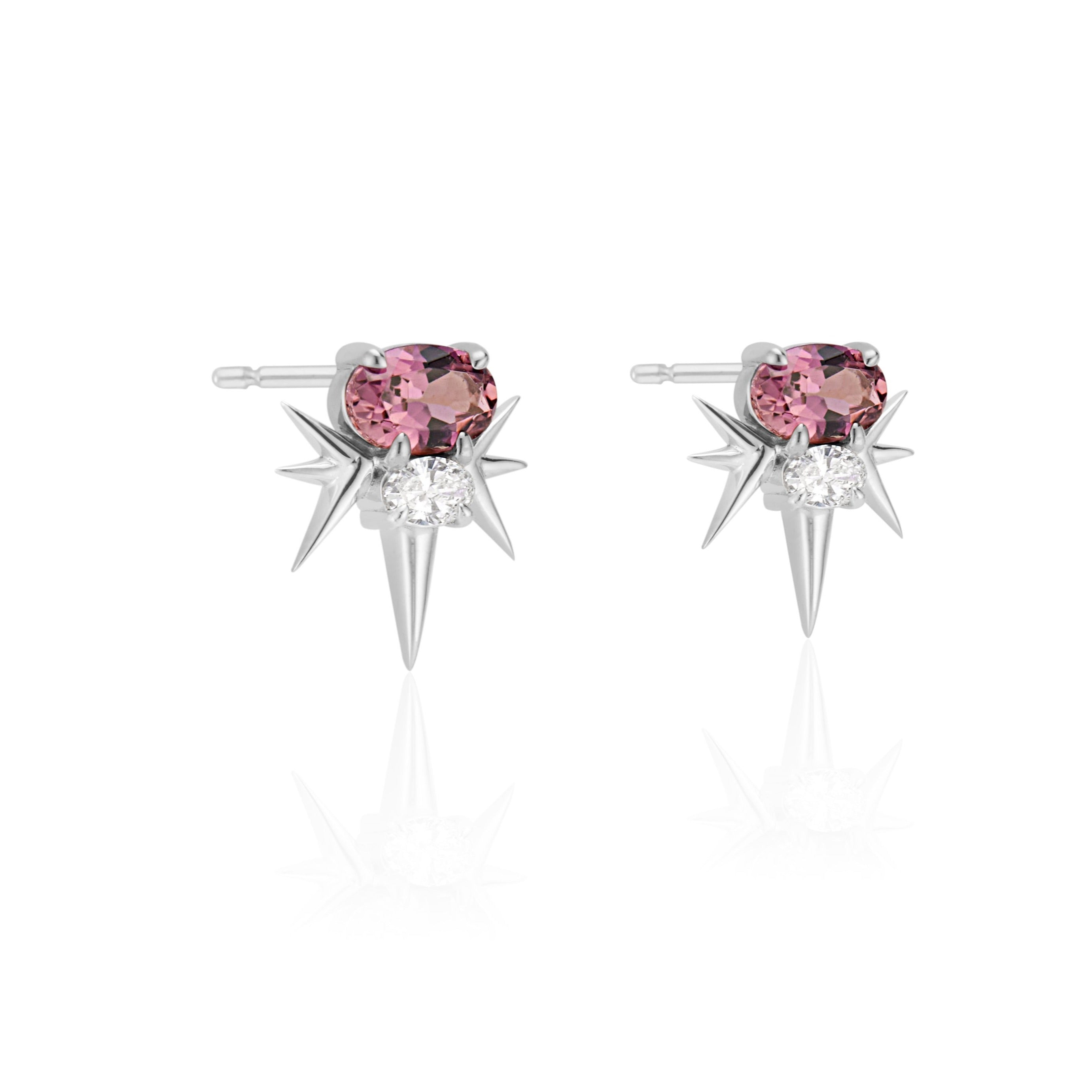 Pair of white gold star-shaped earrings with oval-shaped pink tourmaline gemstone and small diamonds, against white background.