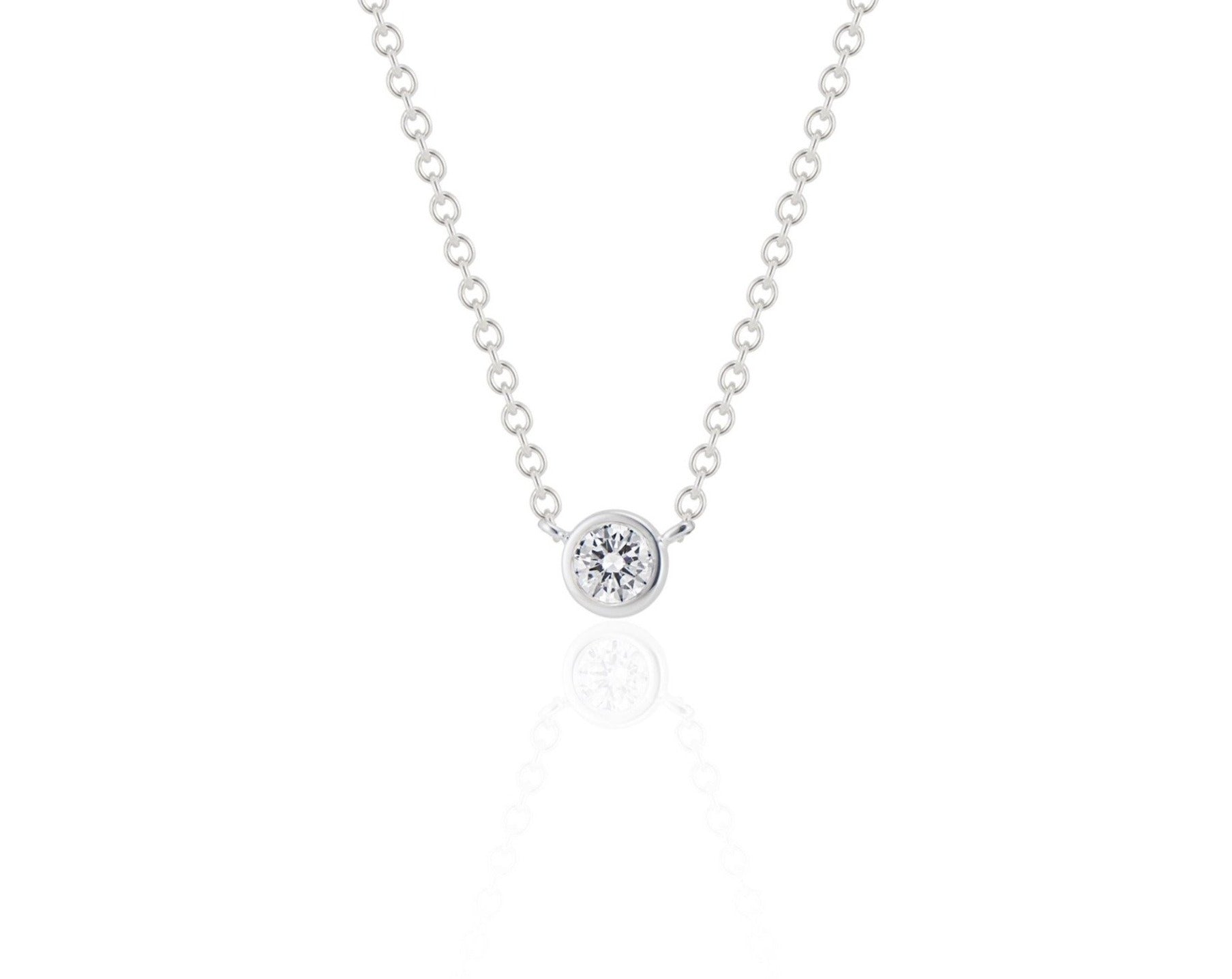 Front view of a round brilliant cut diamond necklace sitting upright. The diamond is set in a white gold round bezel setting. The white gold round-link chain connects at each side of the bezel setting. 