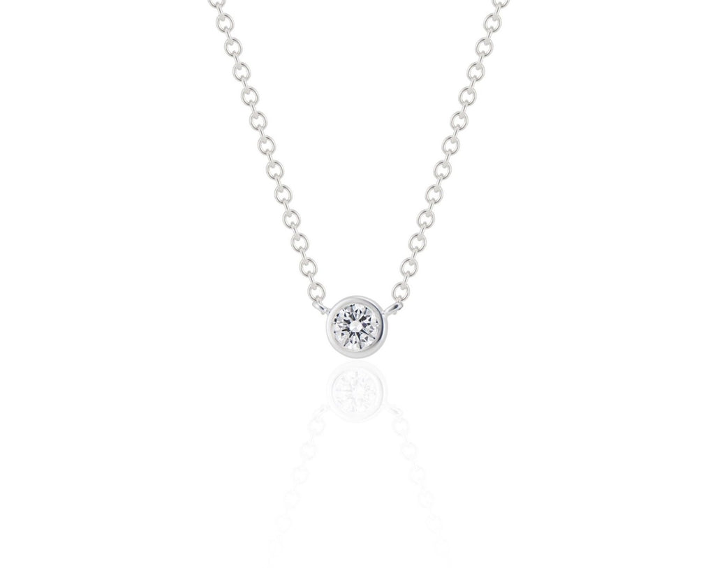 Front view of a round brilliant cut diamond necklace sitting upright. The diamond is set in a white gold round bezel setting. The white gold round-link chain connects at each side of the bezel setting. 