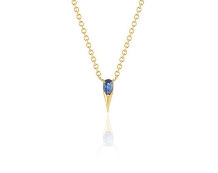  Front view of unique blue sapphire pendant necklace connected to a yellow gold round-link chain by 2 angled yellow gold prongs. The pear-shaped blue sapphire stone is set at the top of a yellow gold spike that drops below, forming a water droplet shape. 