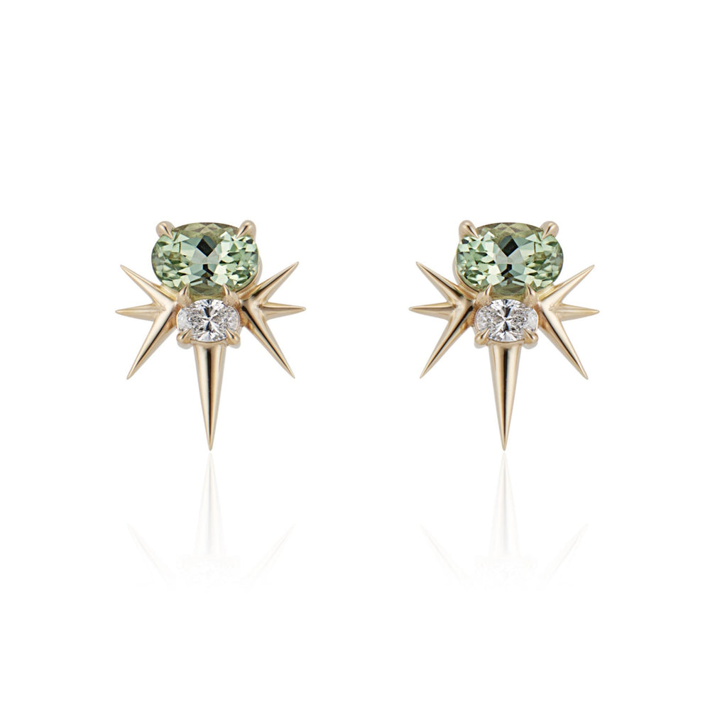 Front view of yellow gold spike earrings, each featuring 1 horizontal oval-shaped green tourmaline stone with 1 oval-shaped diamond below. 7 yellow gold spikes extend out from the diamond, 3 on either side and 1 slightly longer spike pointed down. 