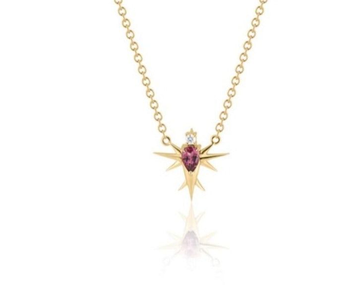 Front view of abstract bird pendant necklace connected to a Yellow gold round-link chain. A pear-shaped pink tourmaline stone forms the bird’s body, topped with a round diamond head. Yellow gold spikes extend from the body to form wings and a tail. 