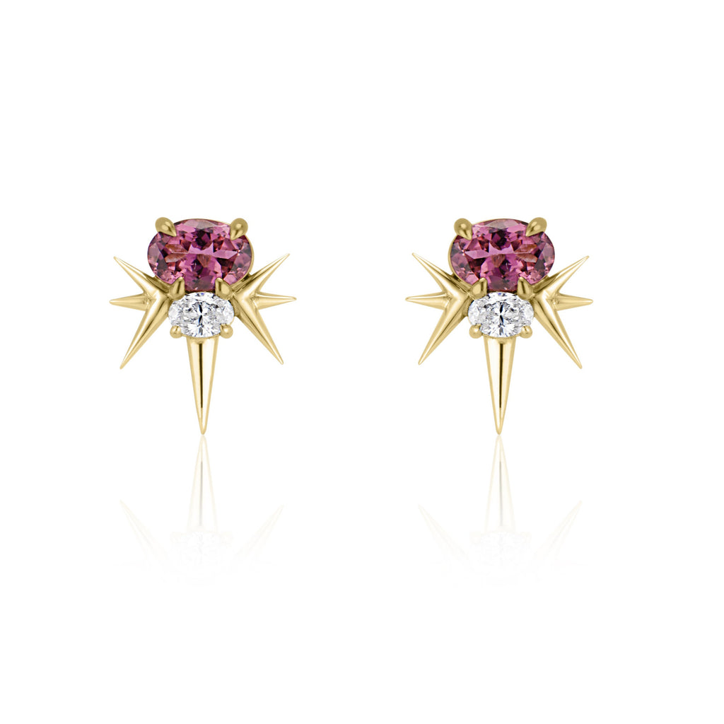  Front view of yellow gold spike earrings, each featuring 1 horizontal oval-shaped pink tourmaline stone with 1 oval-shaped diamond below. 7 yellow gold spikes extend out from the diamond, 3 on either side and 1 slightly longer spike pointed down. 
