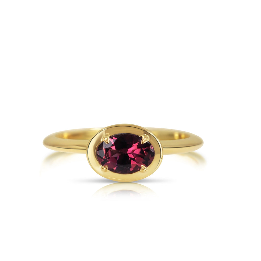 Top view of the hand-crafted pink tourmaline filigree ring. The oval-shaped pink tourmaline gemstone is fixed with 4 prongs and set in a beveled oval-shaped yellow gold basket that compliments the beveled band.